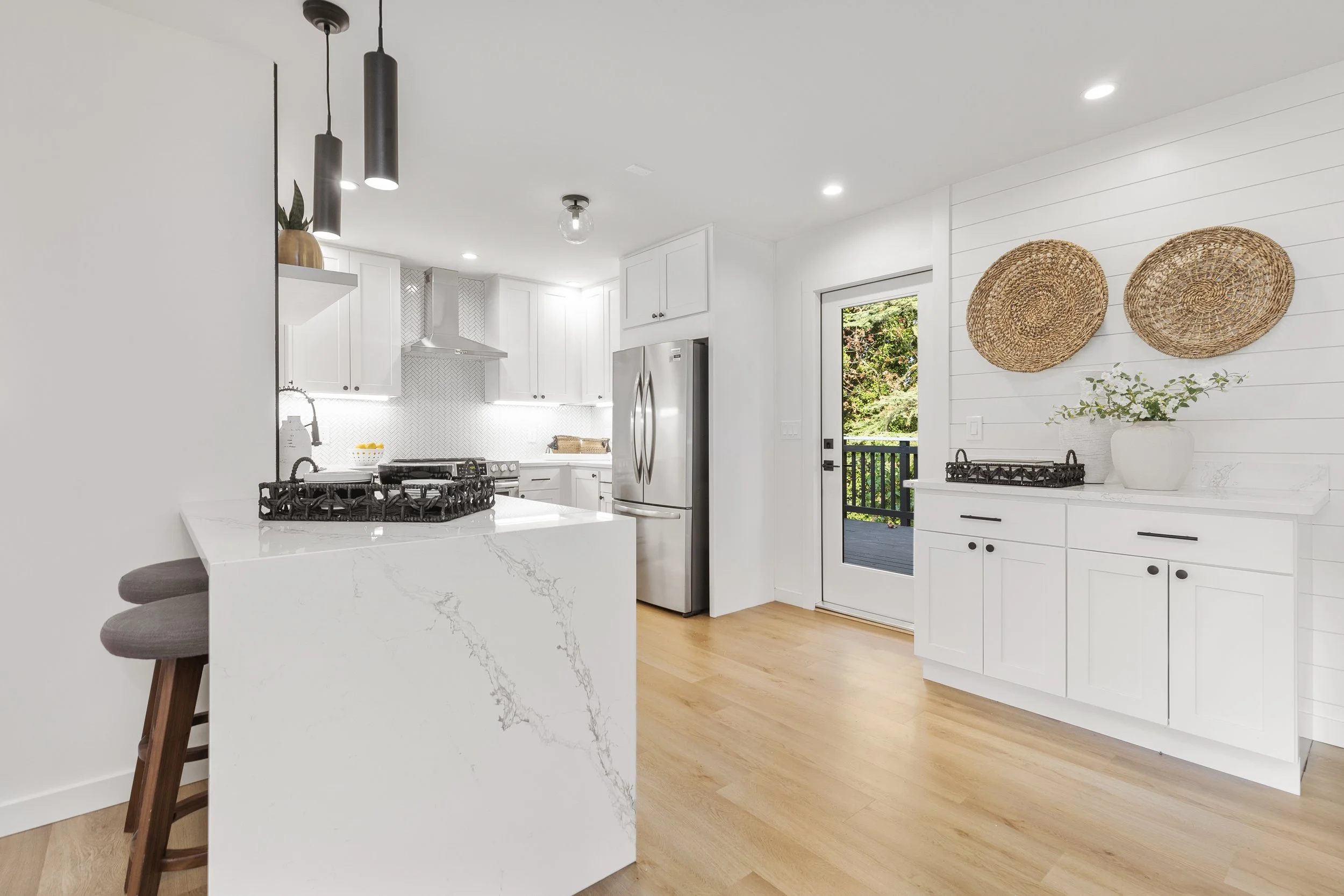 Kitchen island with waterfall quartz countertop, stainless refrigerator, and glass door to backyard — Bothell, Seattle full home remodel