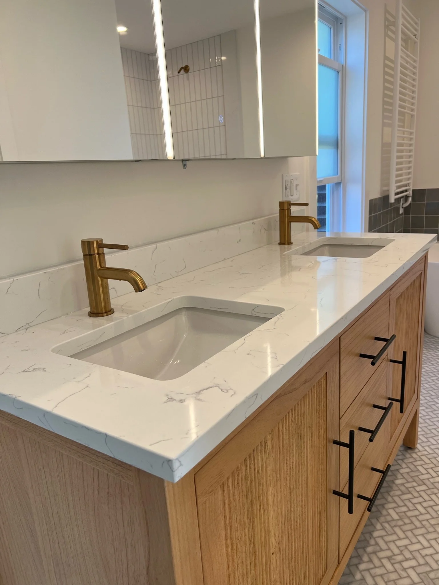 Close-up of vanity sink with brass faucet and quartz countertop — Viewmont, Seattle primary bath remodel