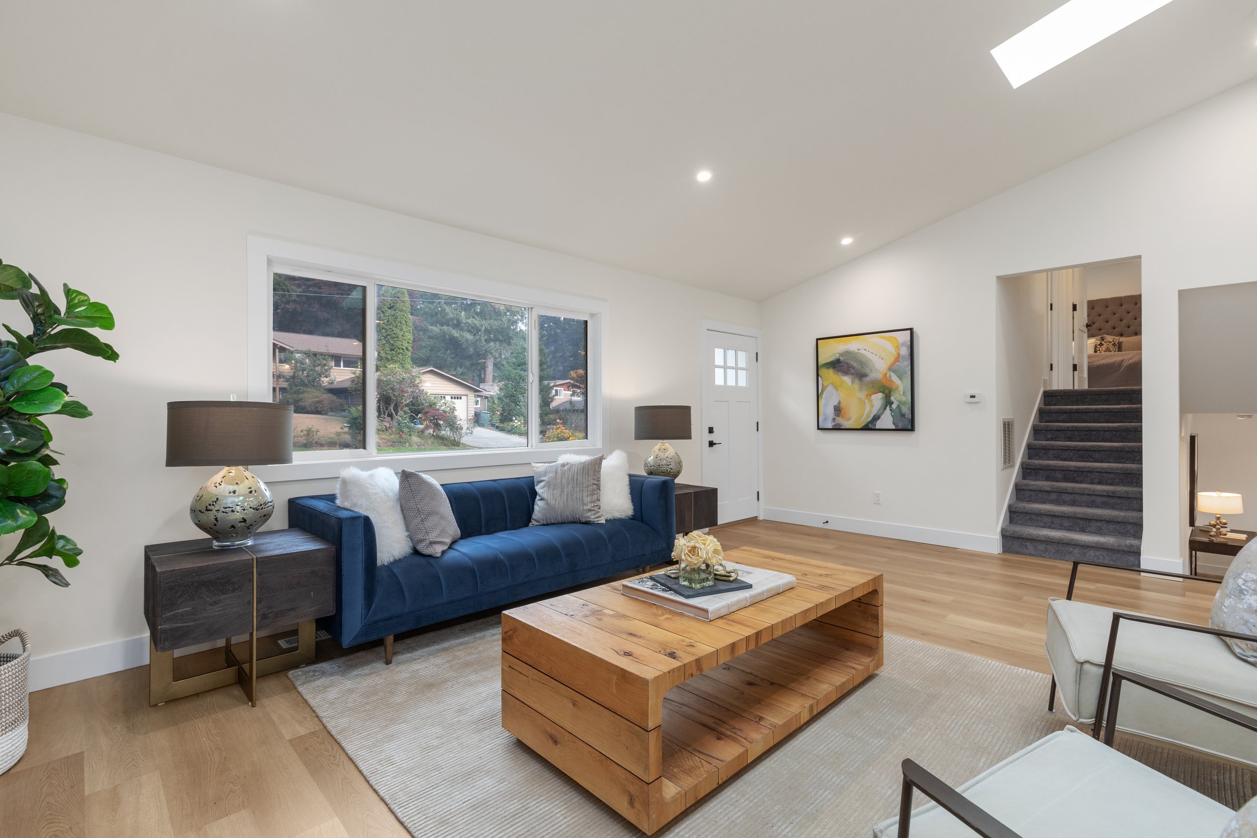 Living room with navy sofa, wood coffee table, and view toward the staircase and skylights — Kenmore, Seattle addition remodel