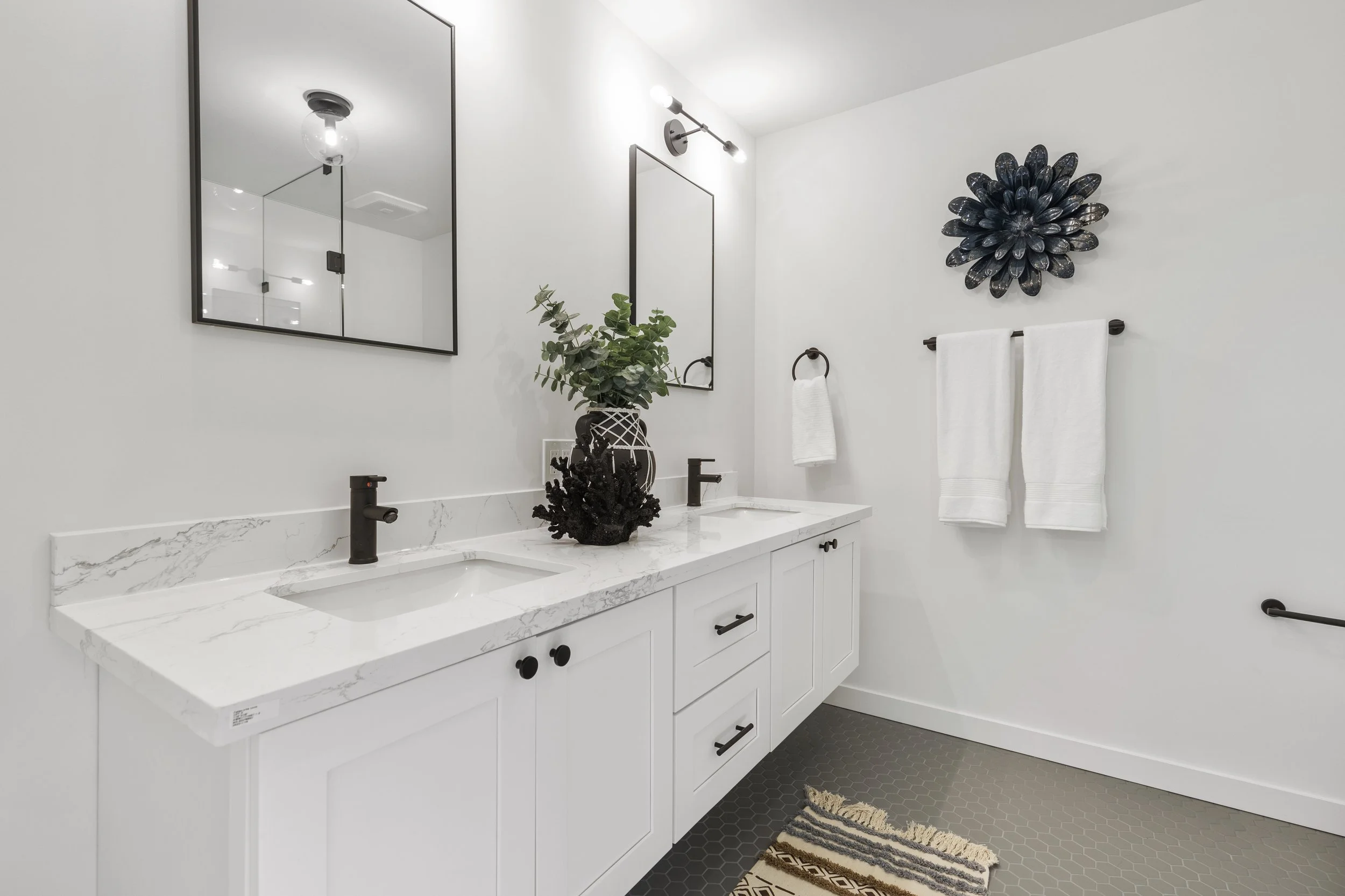Bathroom double vanity with white cabinetry, black hardware, and decorative sunburst mirror accent — Bothell, Seattle full home remodel