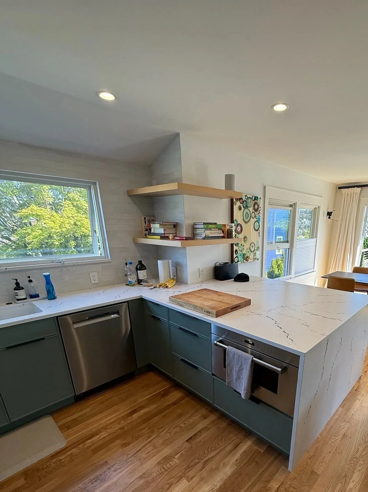 Kitchen island with white waterfall quartz countertop and sage green cabinetry, open to dining area — Wallingford, Seattle kitchen and bath remodel