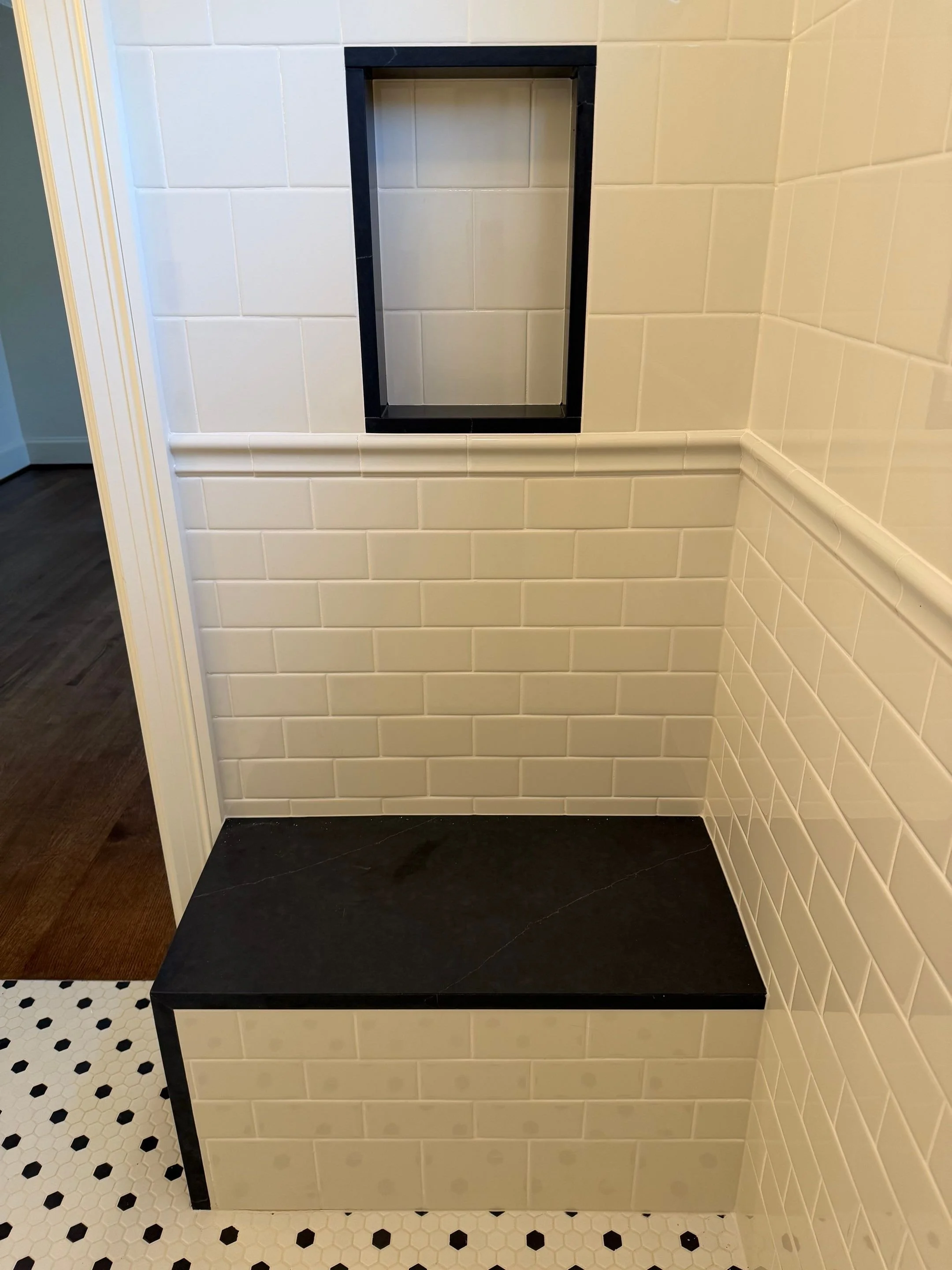 White subway-tiled nook with a black bench seat and patterned tile floor — Discovery Park, Seattle whole-home addition