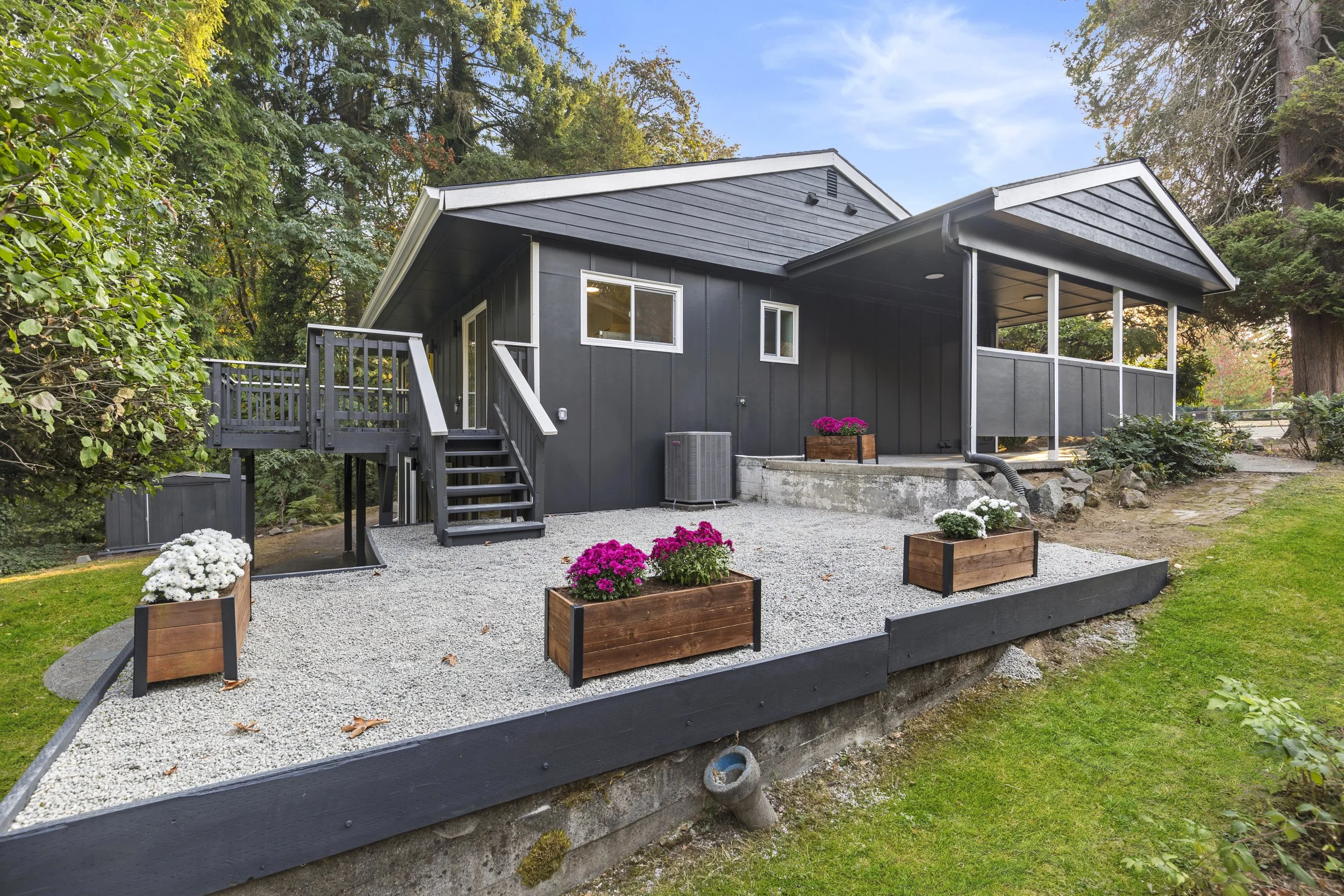 Exterior backyard patio with dark gray siding, gravel patio, and raised planters — Bothell, Seattle full home remodel
