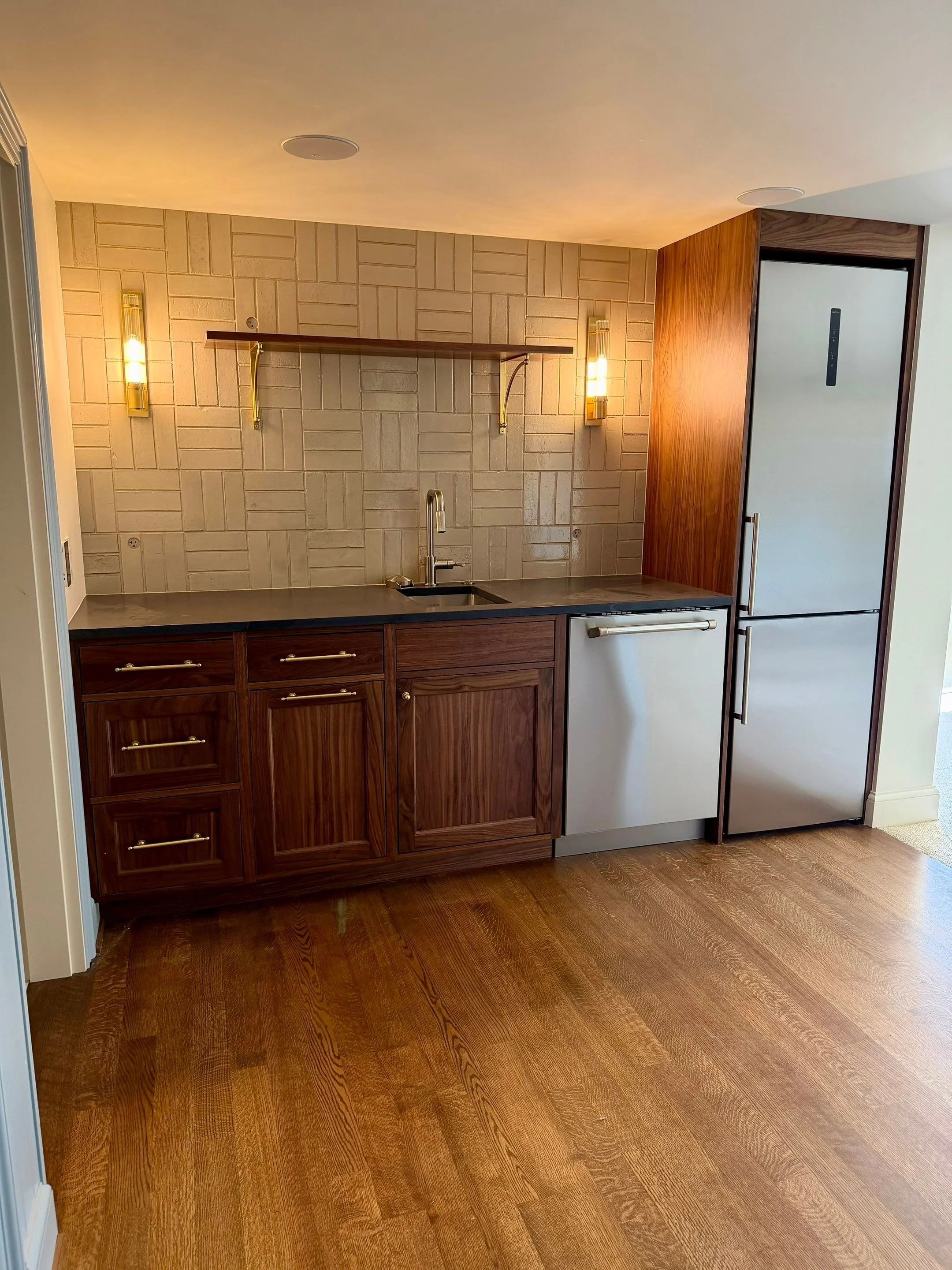 Secondary kitchen with wood cabinetry, brick backsplash, and wall sconces — Discovery Park, Seattle whole-home addition