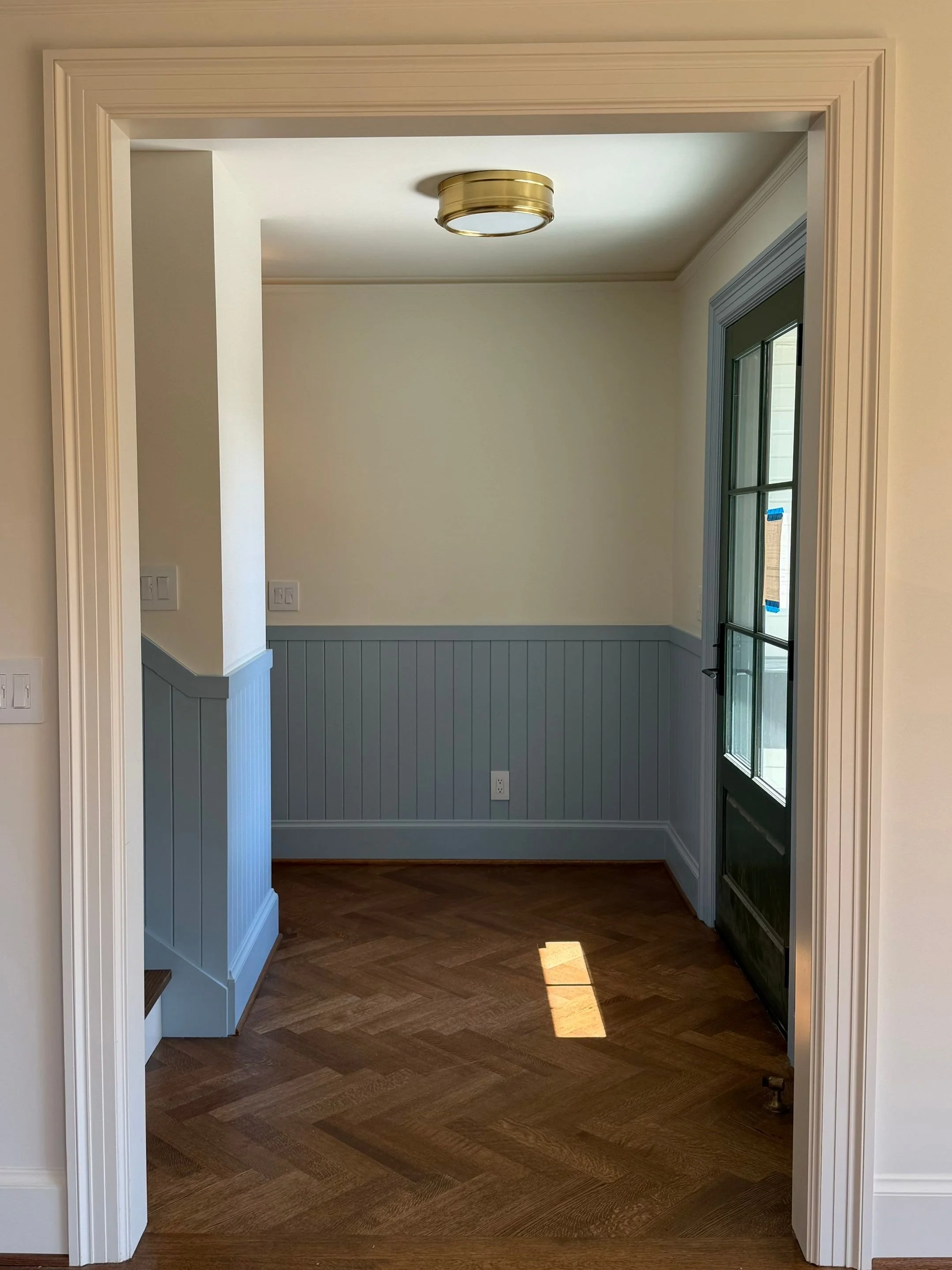 Hallway with blue-gray wainscoting and parquet flooring in the renovated home — Discovery Park, Seattle whole-home addition