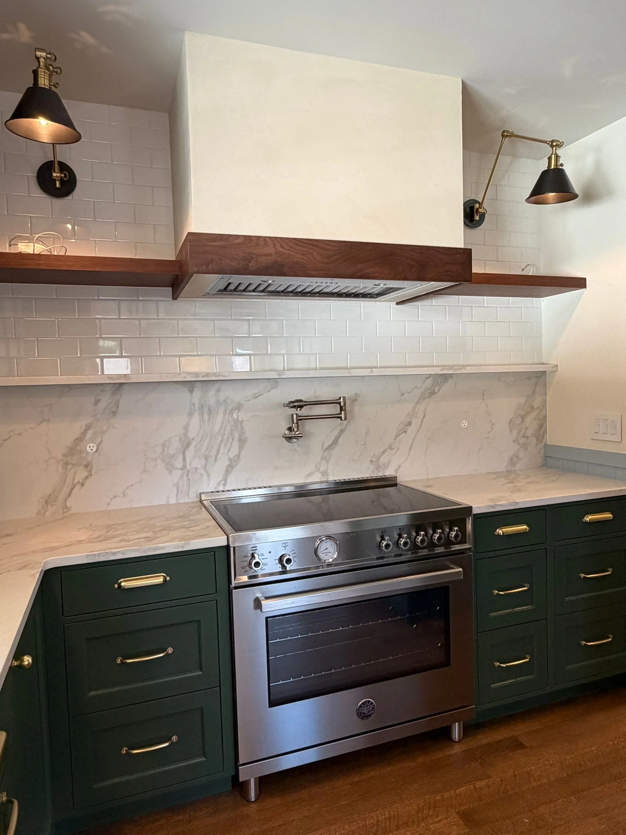 Kitchen with dark green cabinetry, marble backsplash, and gas range — Seattle remodel