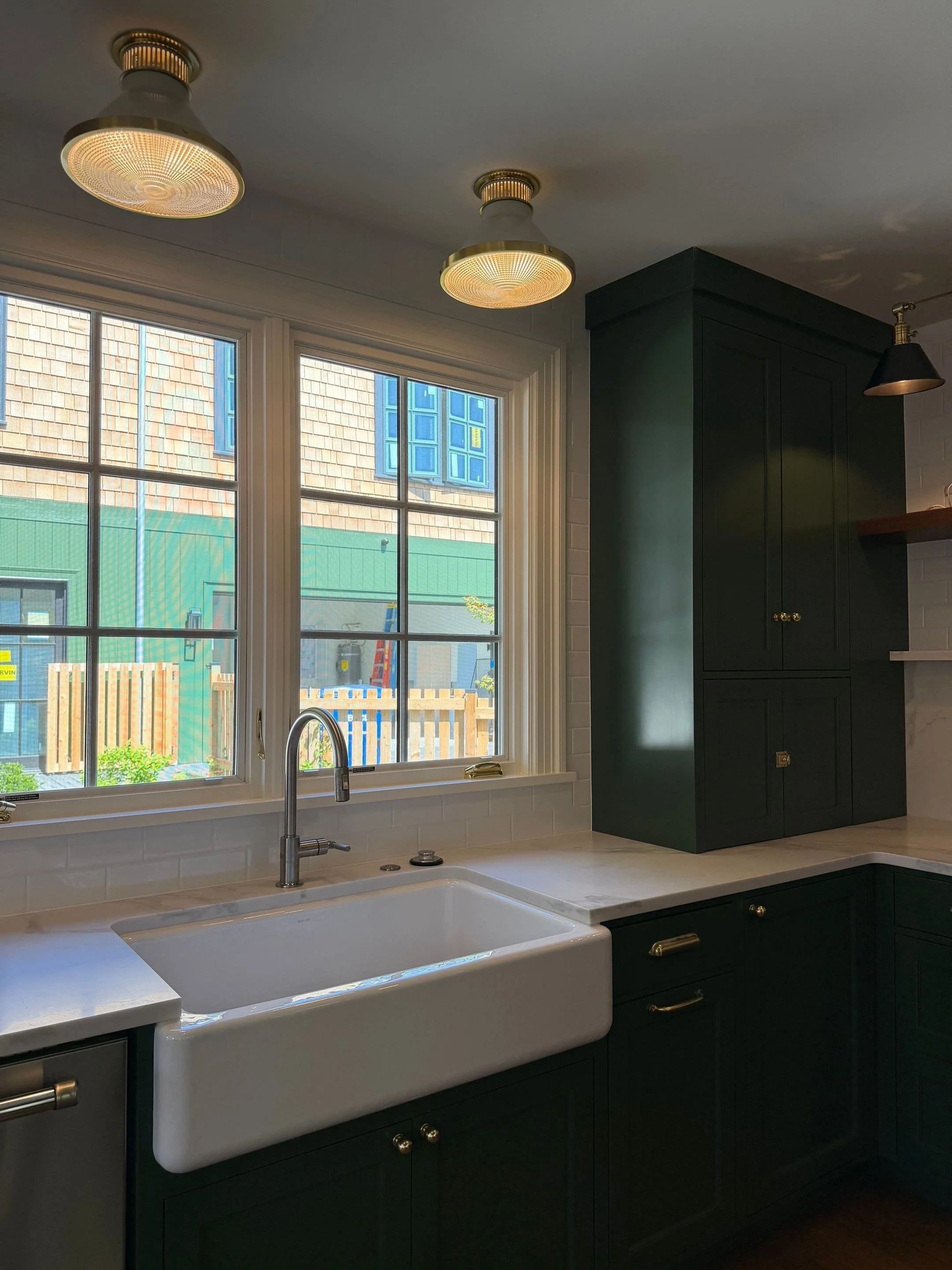 Farmhouse sink with dark green cabinetry beneath large multi-pane windows — Discovery Park, Seattle whole-home addition
