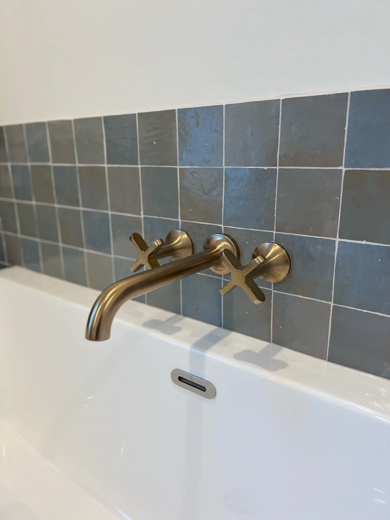 Detail of brass wall-mounted tub filler faucet against blue tile — Viewmont, Seattle primary bath remodel
