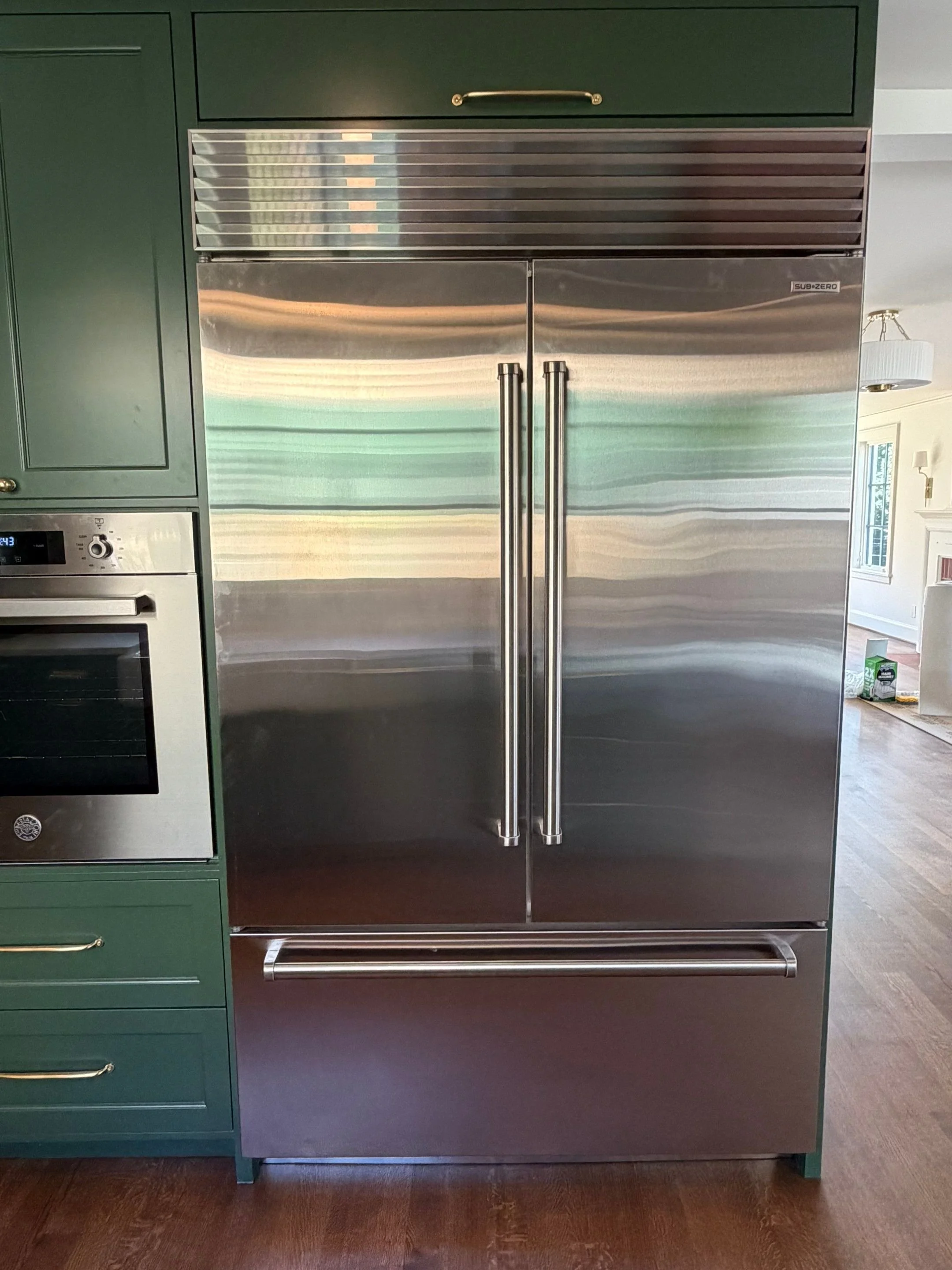 Built-in stainless steel refrigerator flanked by dark green cabinetry — Discovery Park, Seattle whole-home addition