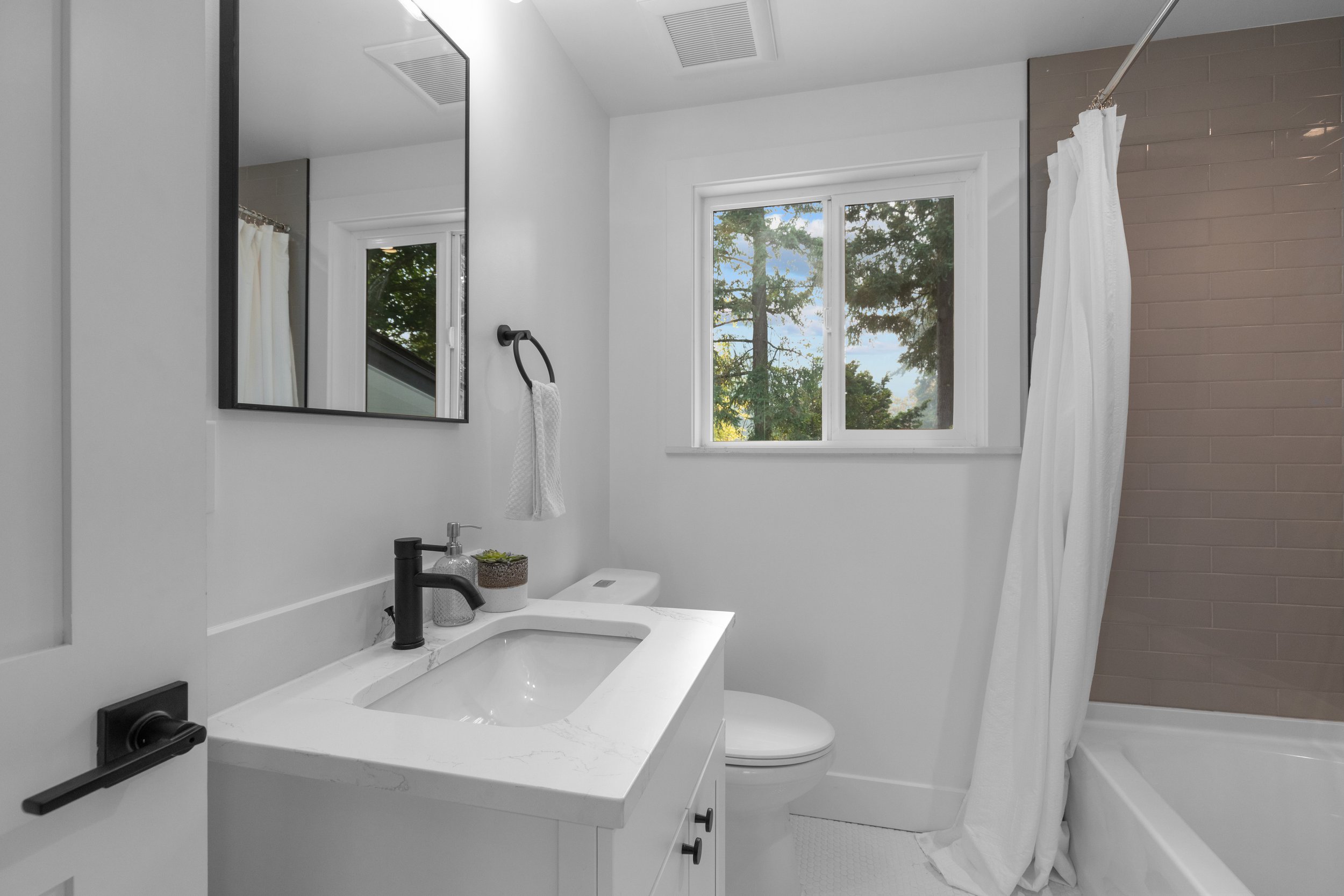 Bathroom with white vanity, framed mirror, toilet, and tub-shower combo — Kenmore, Seattle addition remodel