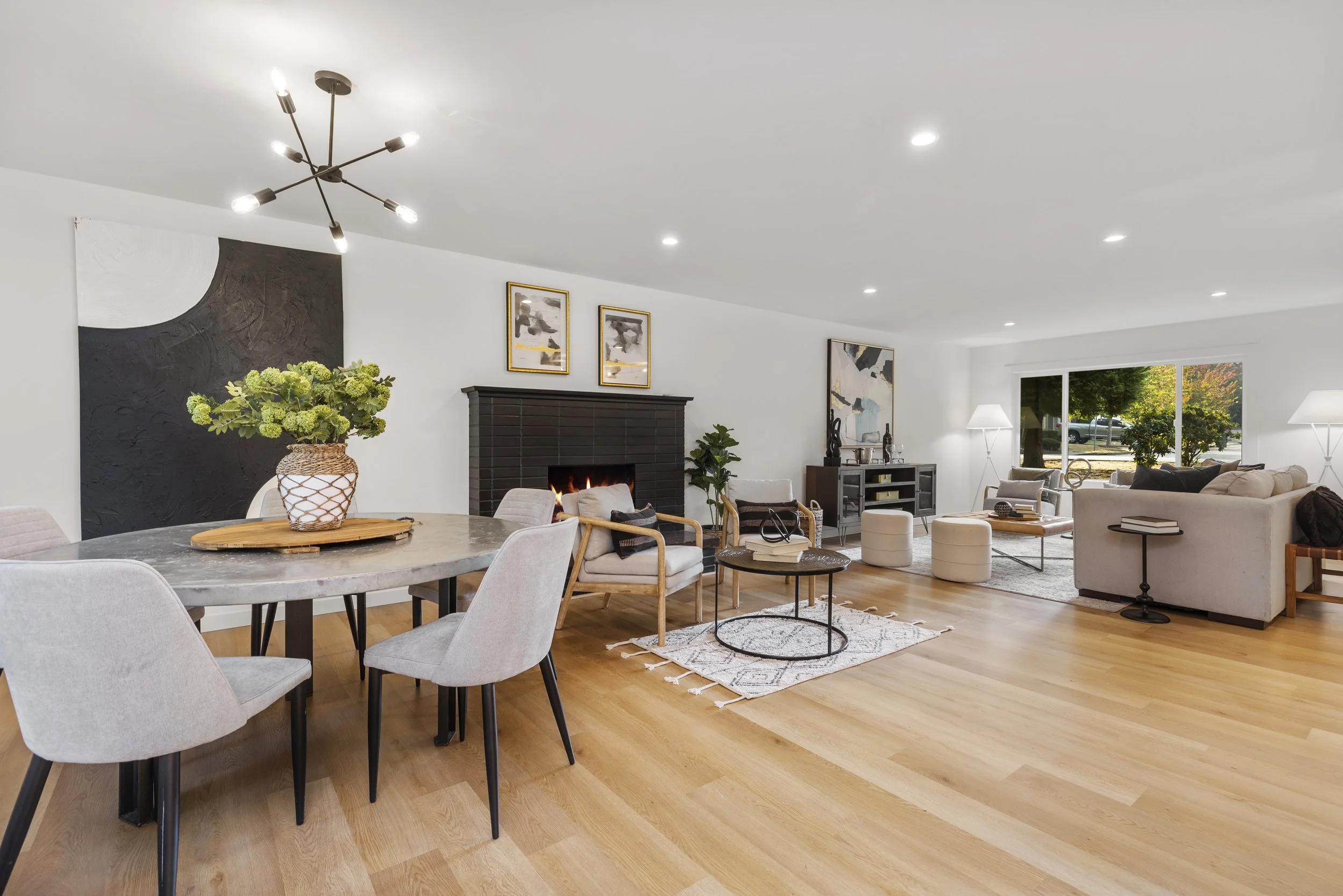 Dining and living room with dark accent wall, round dining table, and modern sputnik chandelier — Bothell, Seattle full home remodel