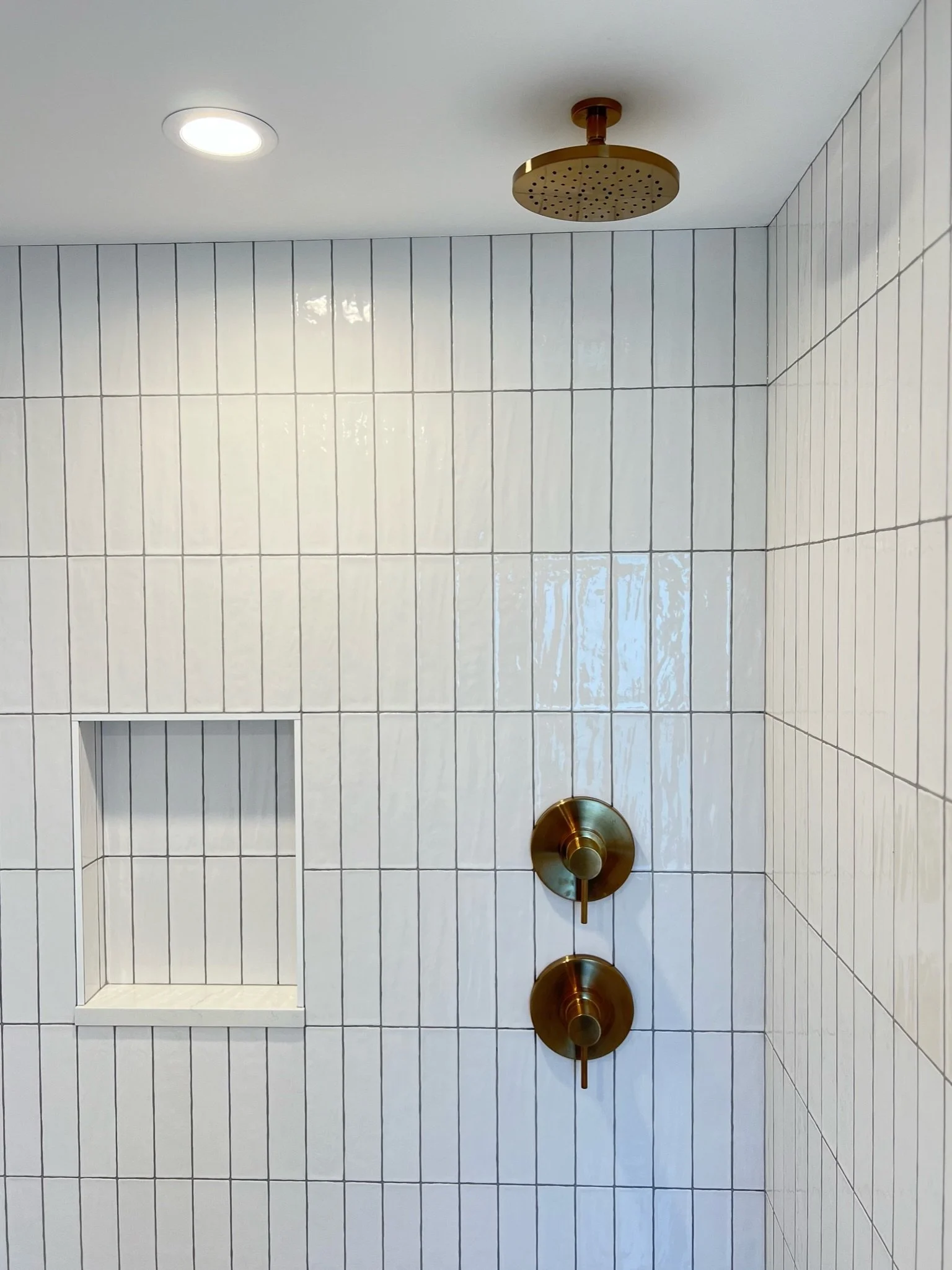 Shower with rain shower head, brass fixtures, white subway tile, and built-in niche — Viewmont, Seattle primary bath remodel