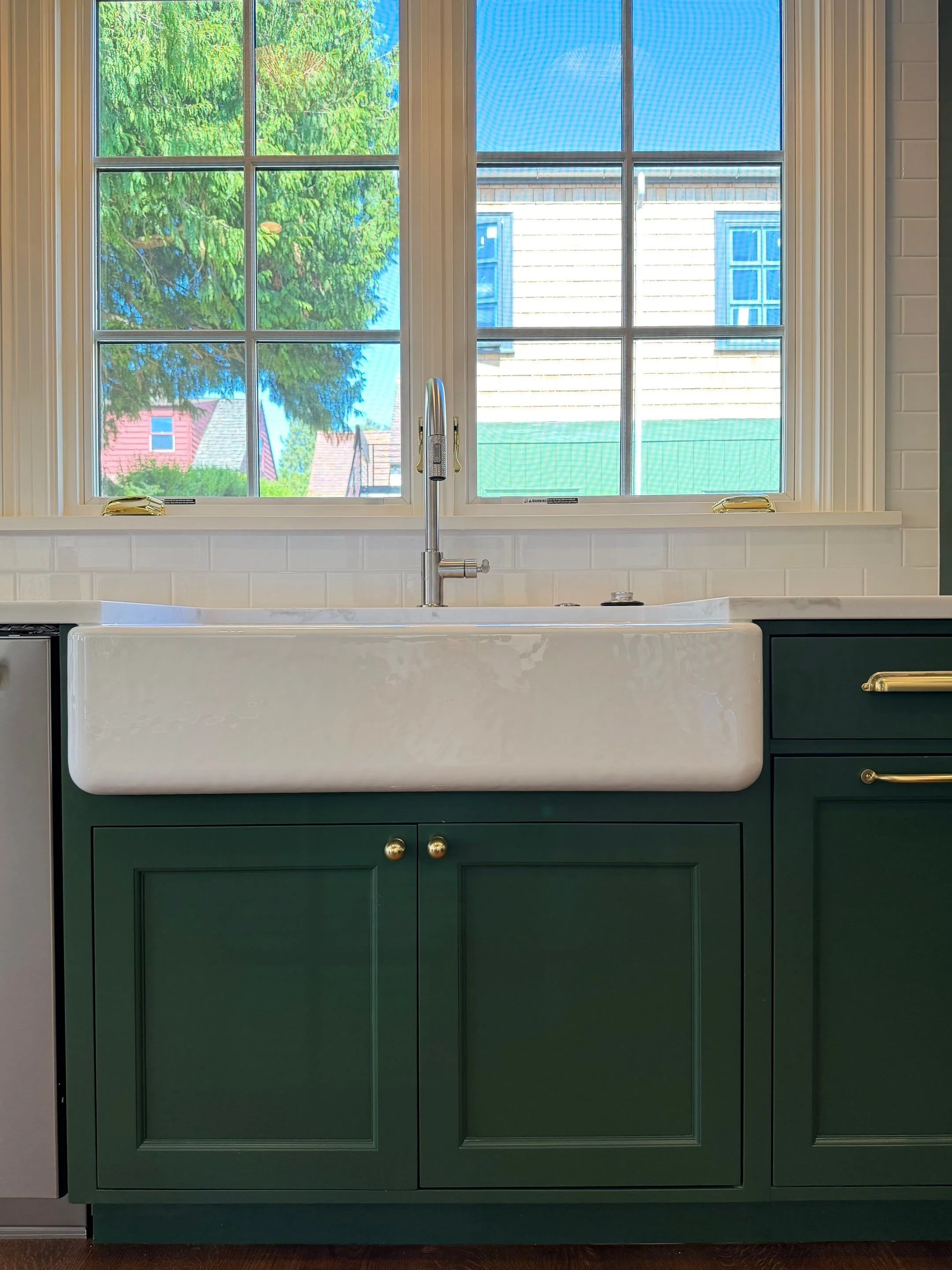 Close-up of the farmhouse sink and dark green cabinetry beneath a window — Discovery Park, Seattle whole-home addition