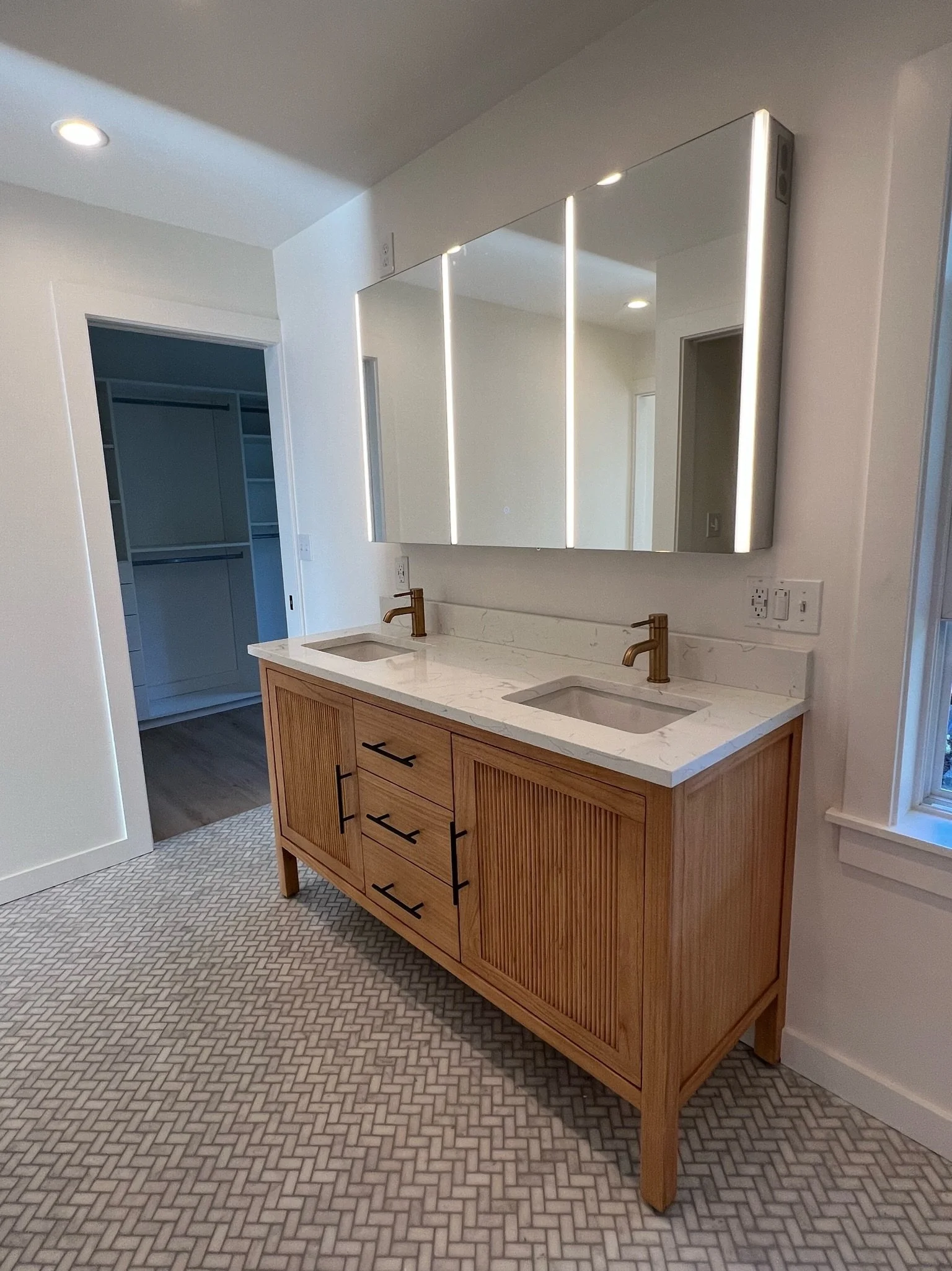 Bathroom vanity with wood cabinetry, navy blue wall, and view toward walk-in closet — Viewmont, Seattle primary bath remodel