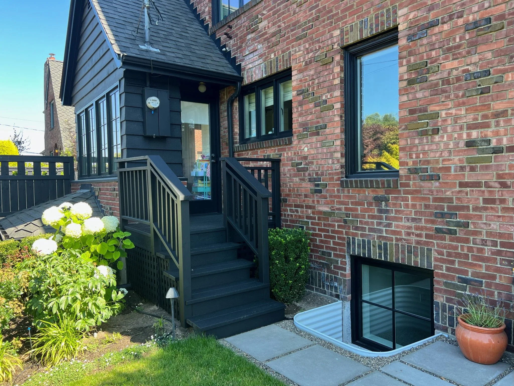 Renovated brick Tudor home exterior with black-framed windows and entry stairs — Magnolia, Seattle full home remodel