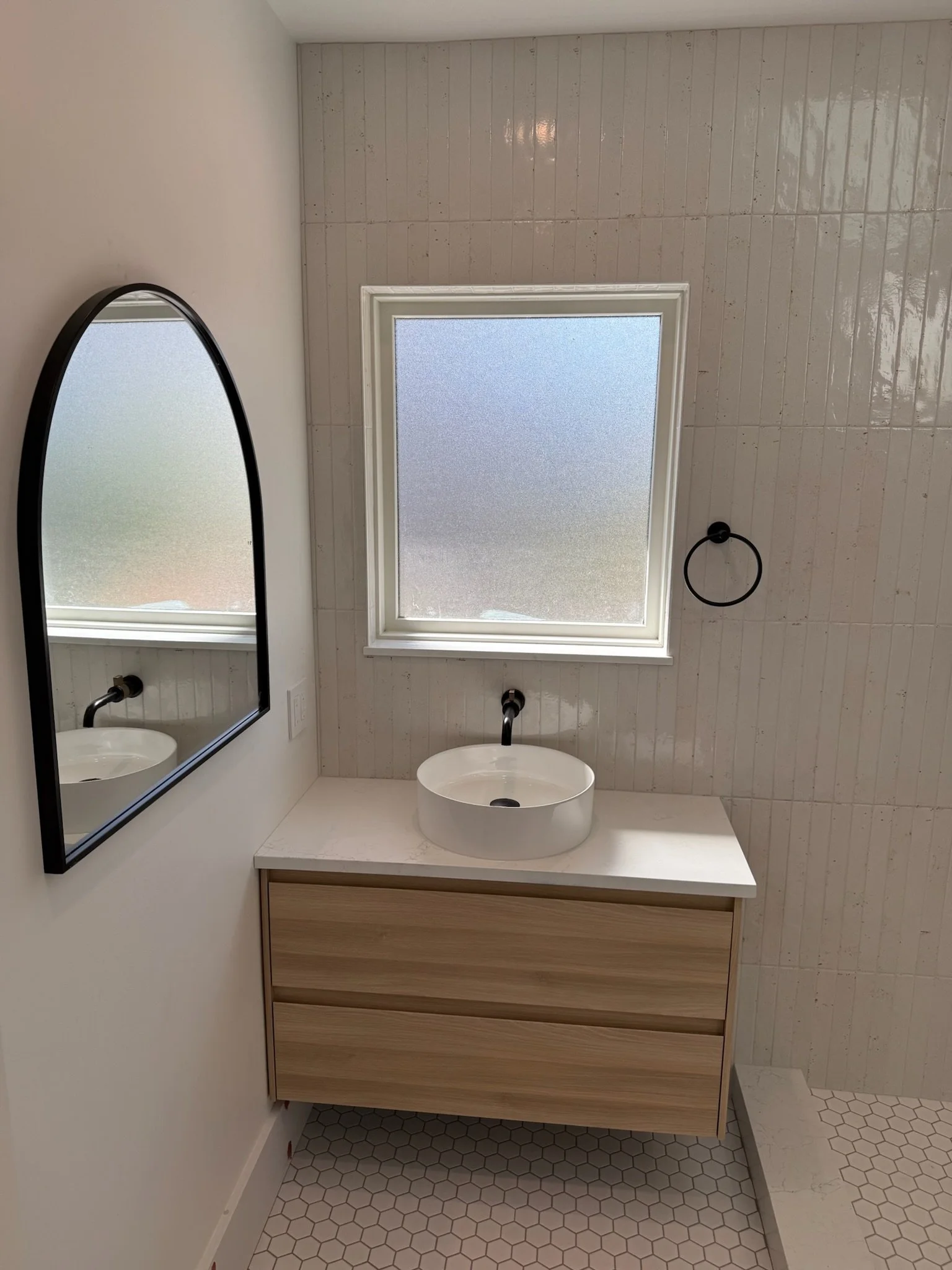 Bathroom vanity with floating wood cabinet, oval mirror, and round sink basin — Wallingford, Seattle kitchen and bath remodel