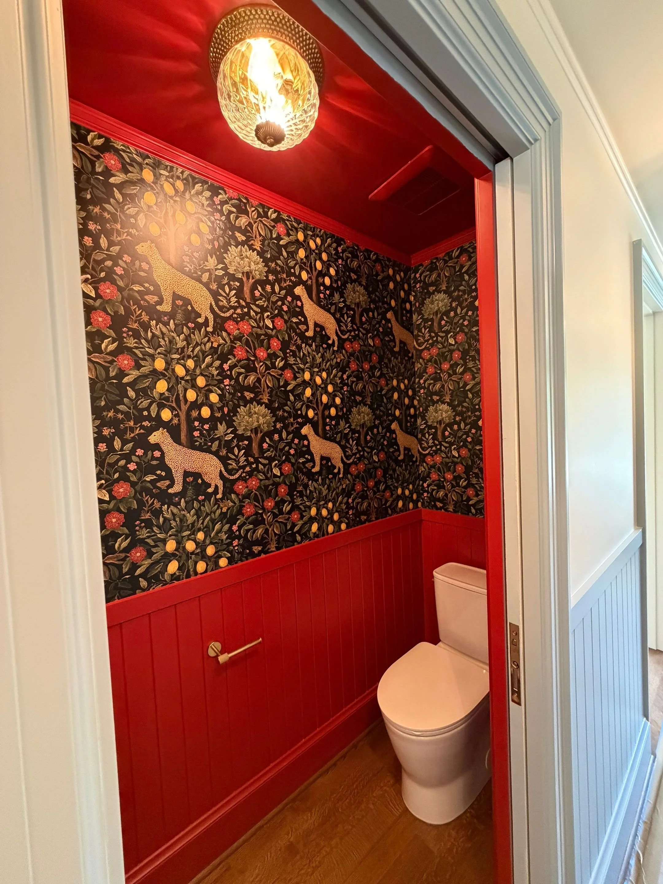 Detail view of the red powder bathroom's toilet and door with statement wallpaper — Discovery Park, Seattle whole-home addition