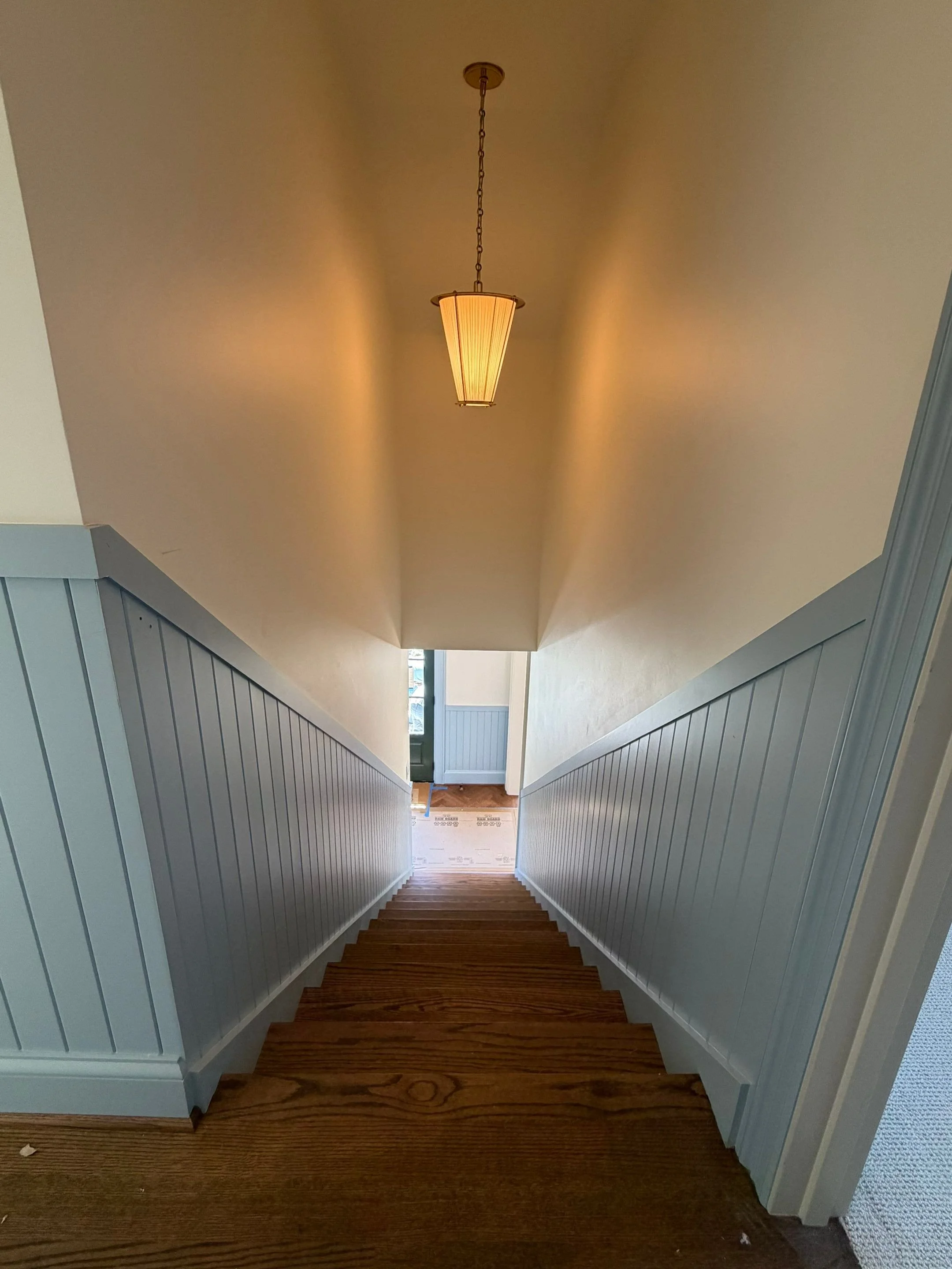 Narrow hallway with blue wainscoting and pendant lighting leading to the stairs — Discovery Park, Seattle whole-home addition