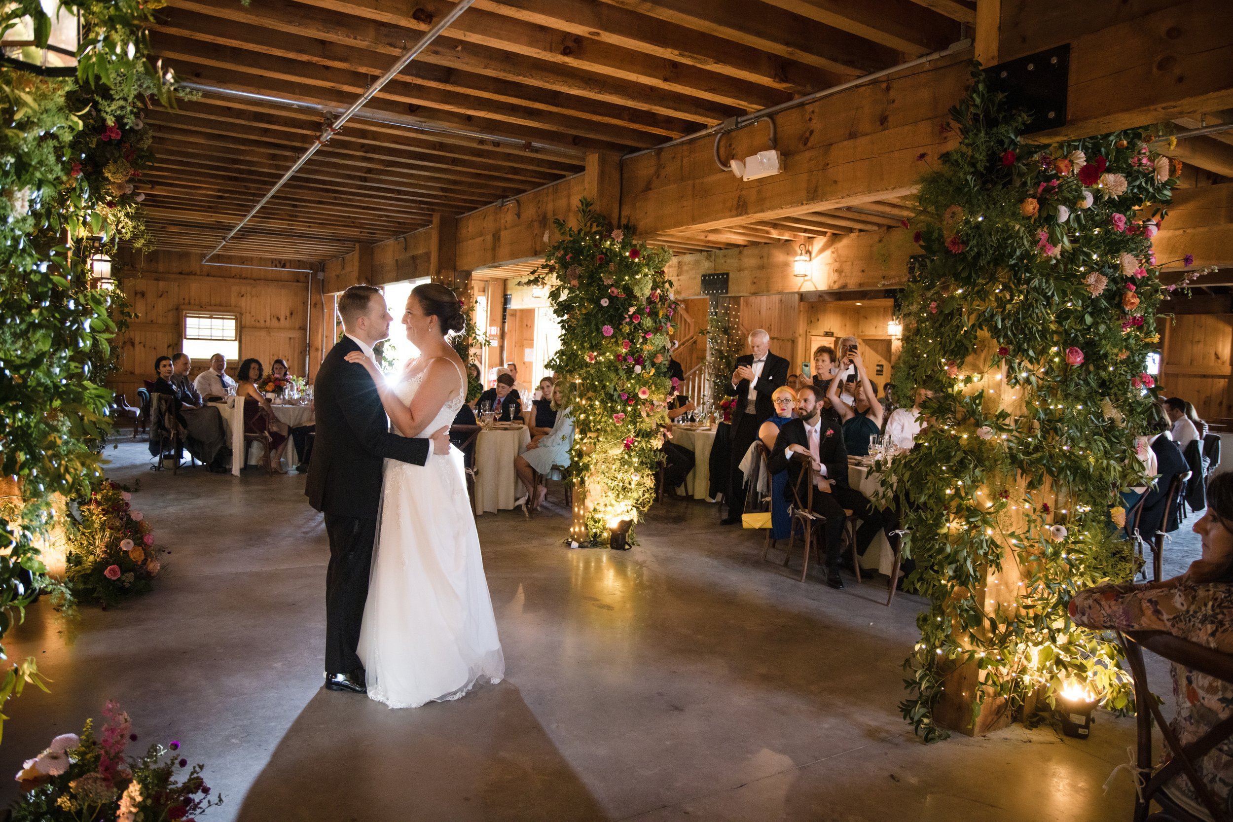 Dramatic barn wedding lighting in Hudson, NY featuring floral uplighting and tiny wire fairy lights by Berkshire Event Lighting