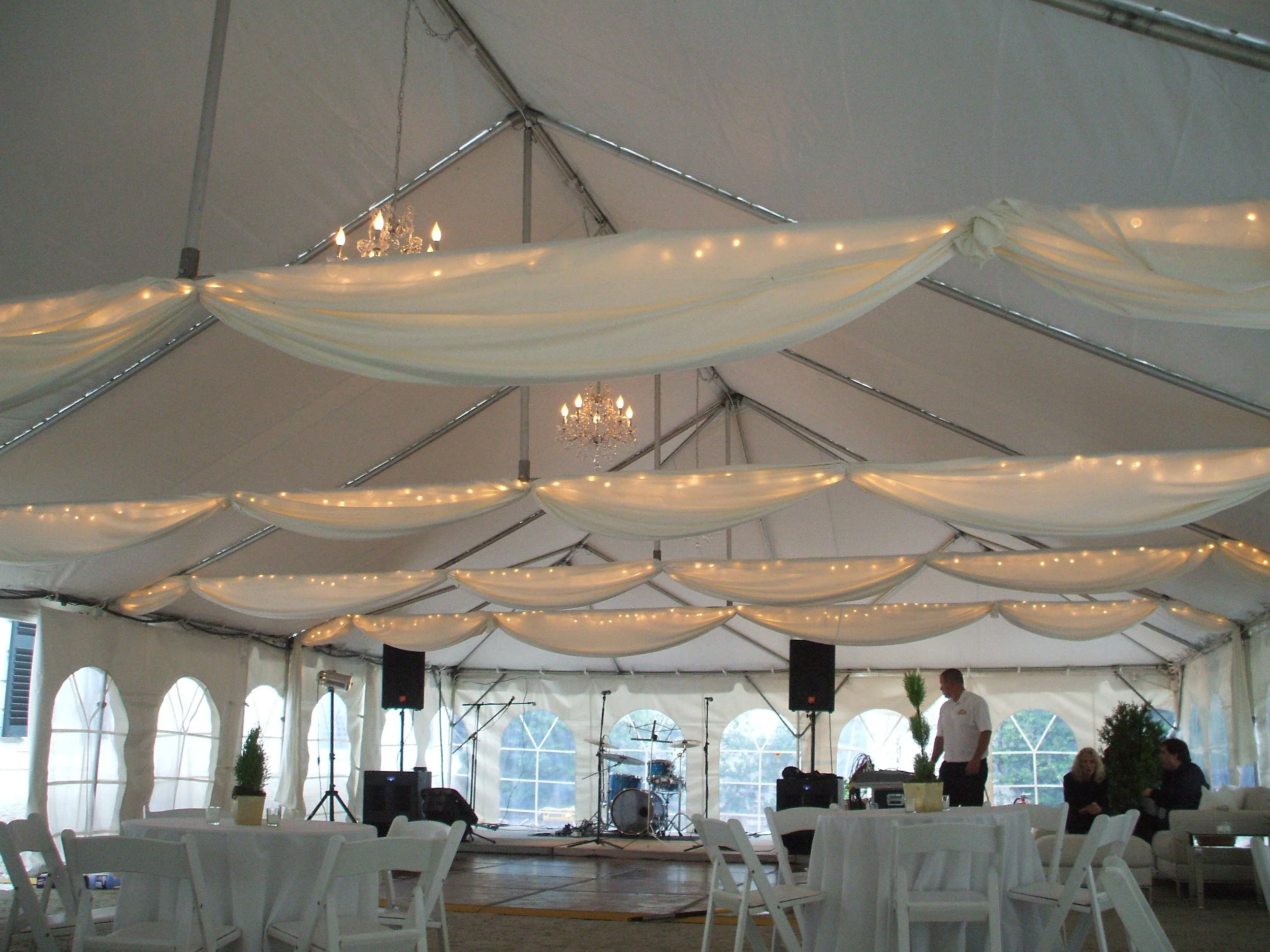 Bespoke twinkle lights diffused through white fabric draping on tent cross poles in a courtyard tent at The Mount, installed by Berkshire Event Lighting.