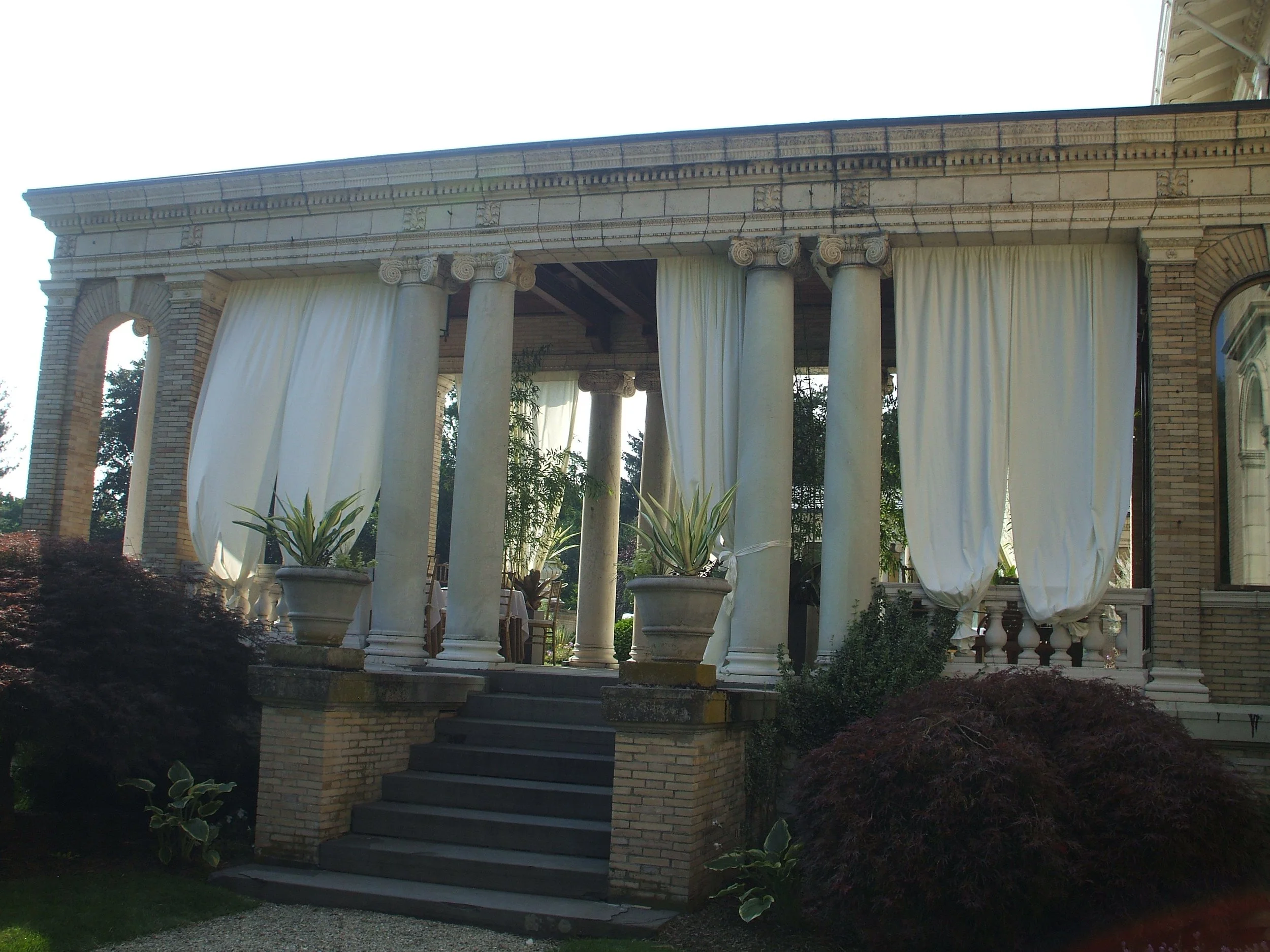 Floor to ceiling white fabric draping on a stone portico column at Wheatleigh in Lenox, installed by Berkshire Event Lighting.