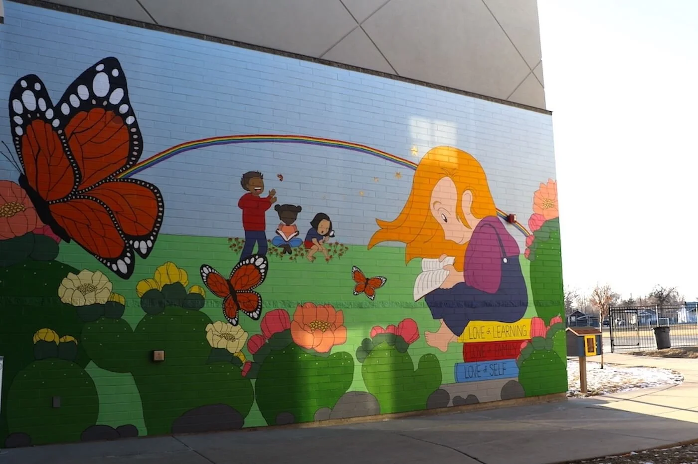 Image shows mural wall in bright colors that is dedicated to teacher.