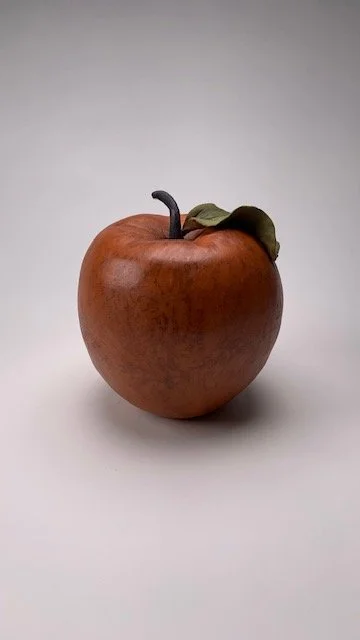 A brown pear-shaped sculpture of a mouse by Pam Brewer against a black and grey background