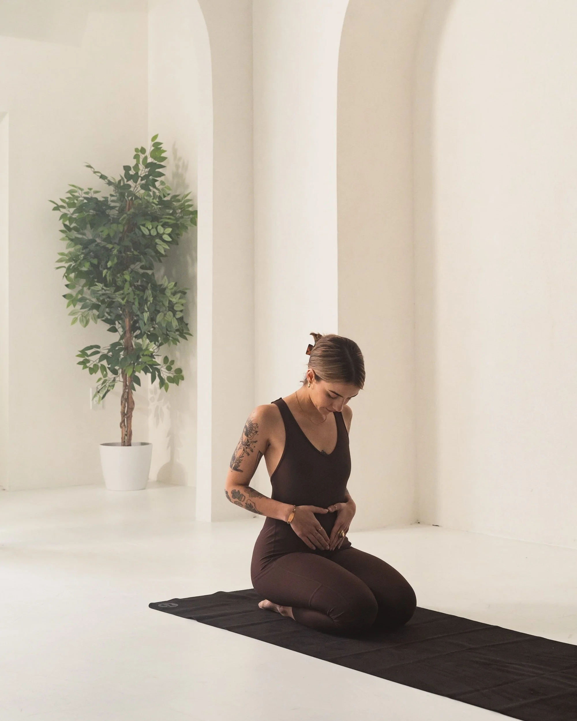Pregnant woman practicing prenatal yoga and somatic movement to support pregnancy, birth preparation, and reproductive health.