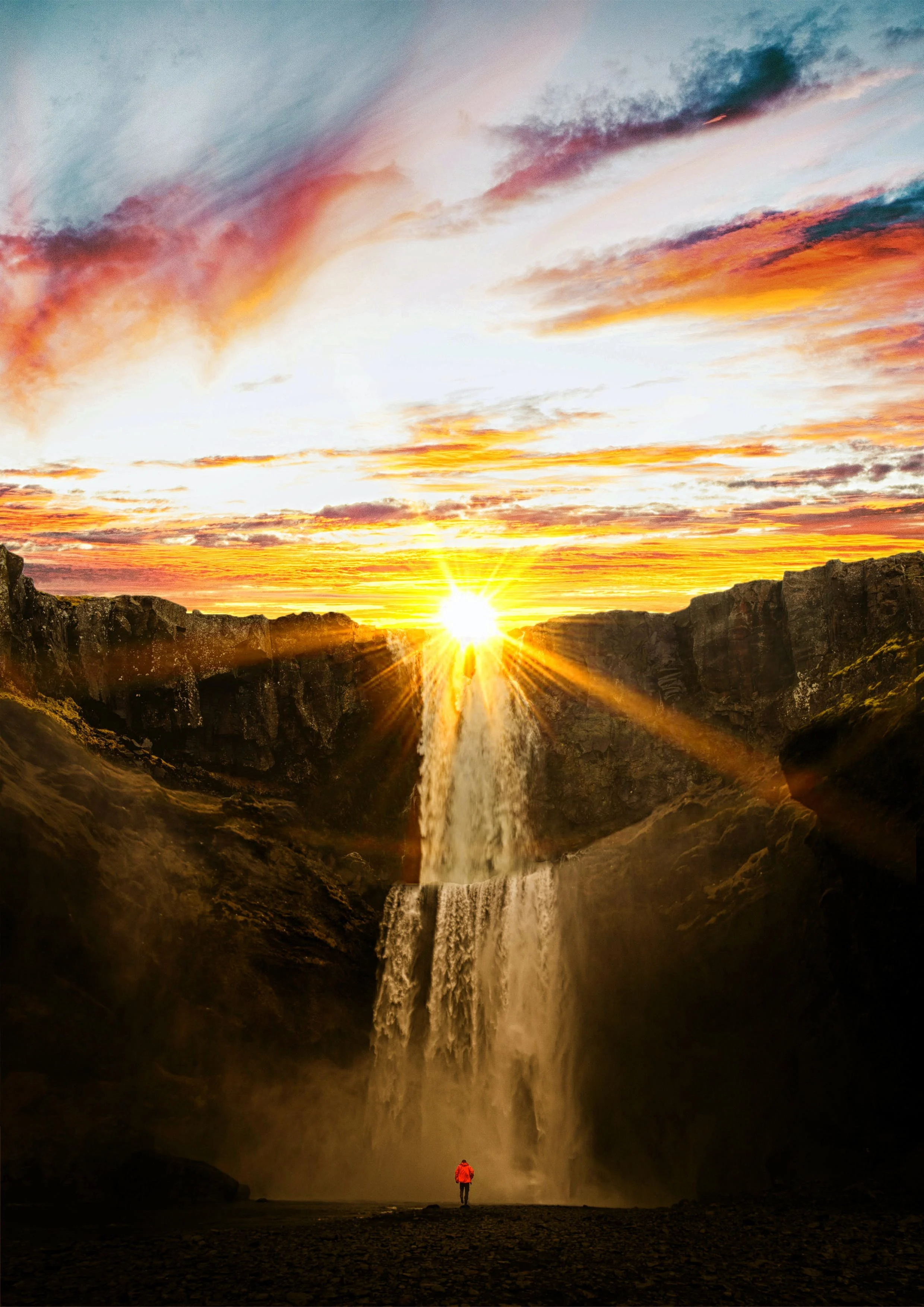 Ground: Intro Package - Image of someone in a red coat standing at the base of a waterfall at sunset