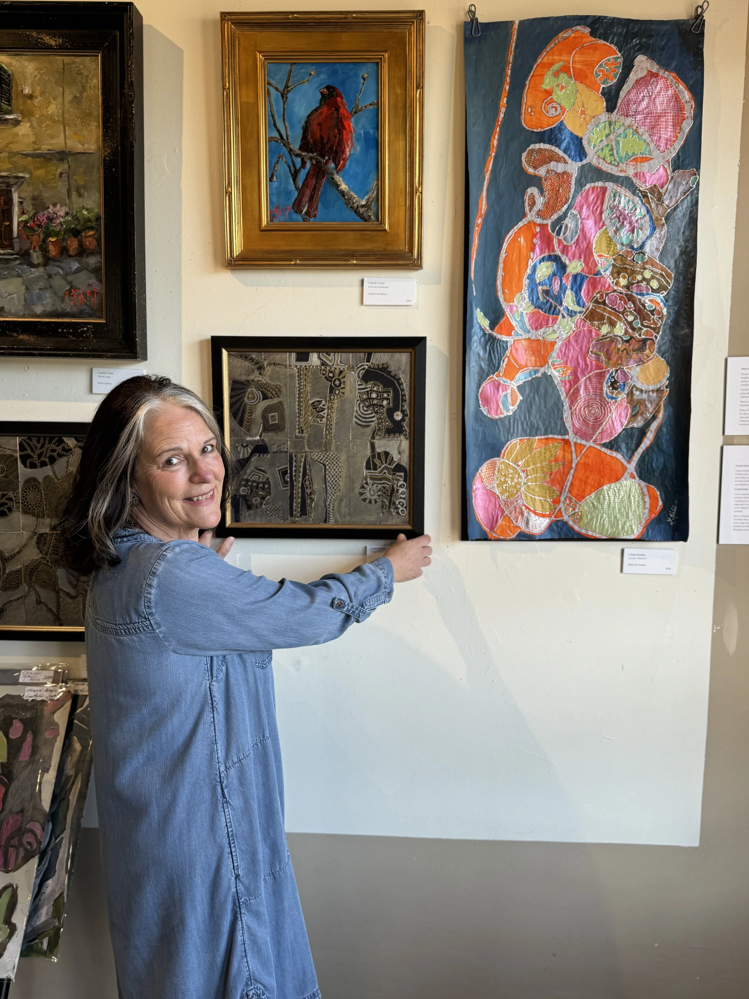 Harriet Runkle, hanging art for a new art exhibit at Frame Gallery Gifts & Art