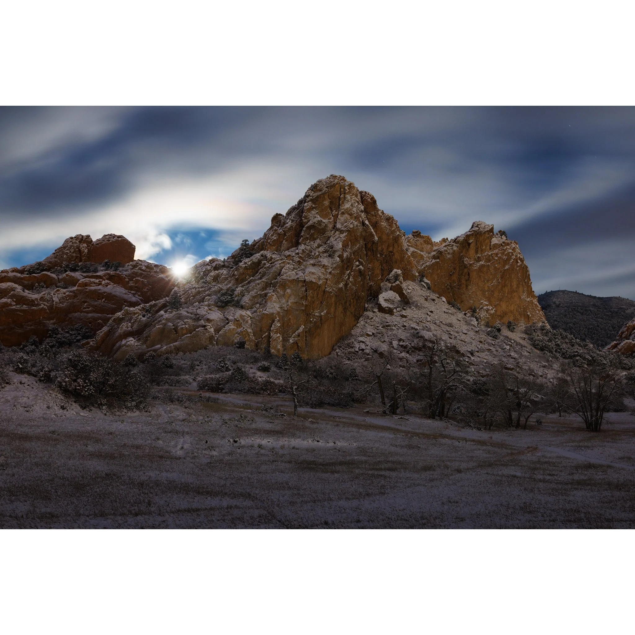 Moonset over snow-covered red rock formations at Garden of the Gods before dawn in Colorado Springs, Colorado.