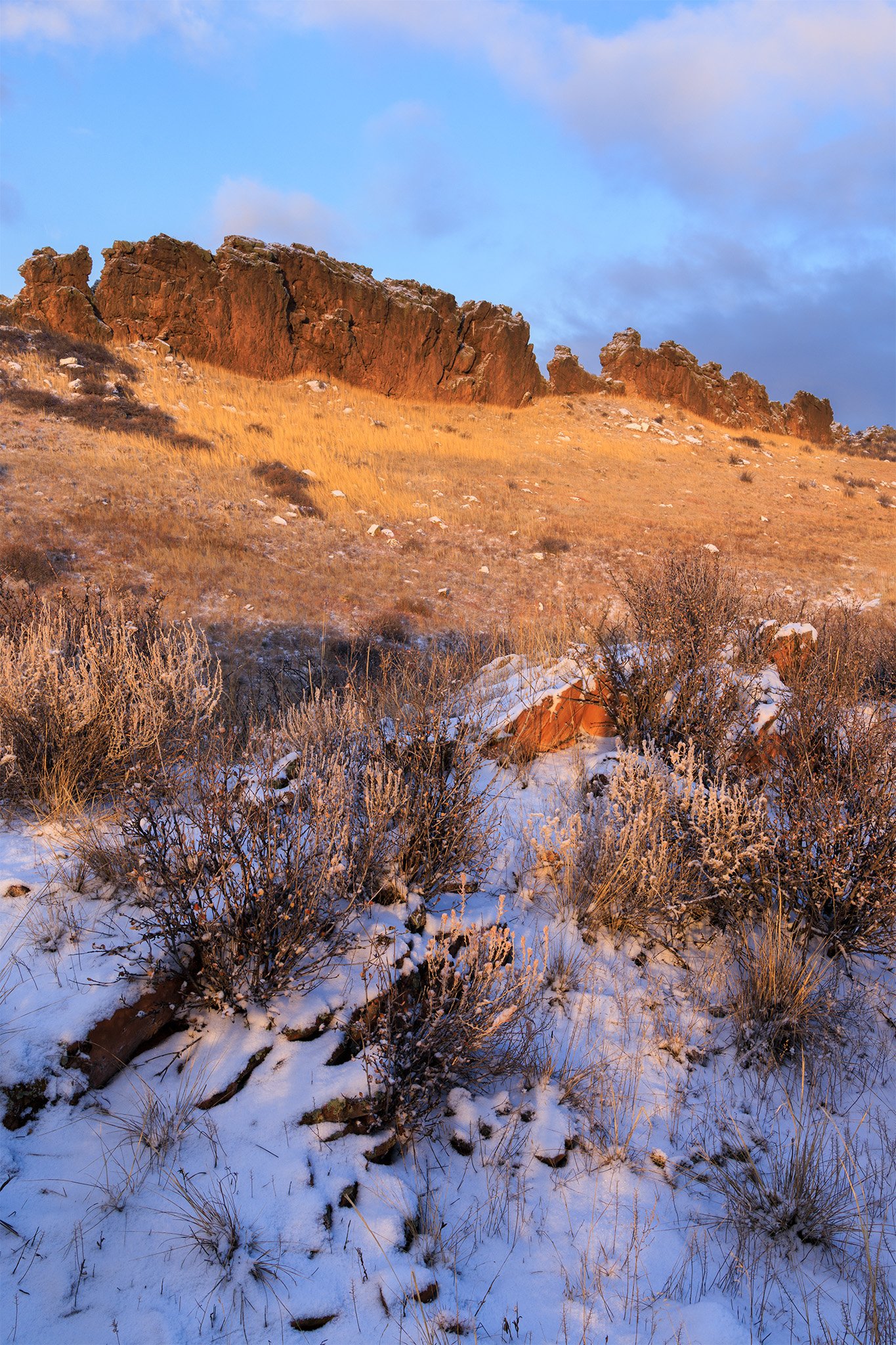 Sunrise light on a sandstone hogback above snowy grassland at Devil's Backbone, Loveland, Colorado.