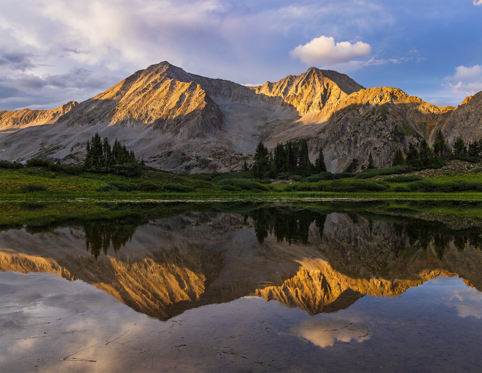 Snowmass Mountain and Hagerman Peak reflected in an alpine tarn at sunset, Maroon Bells-Snowmass Wilderness, Colorado.