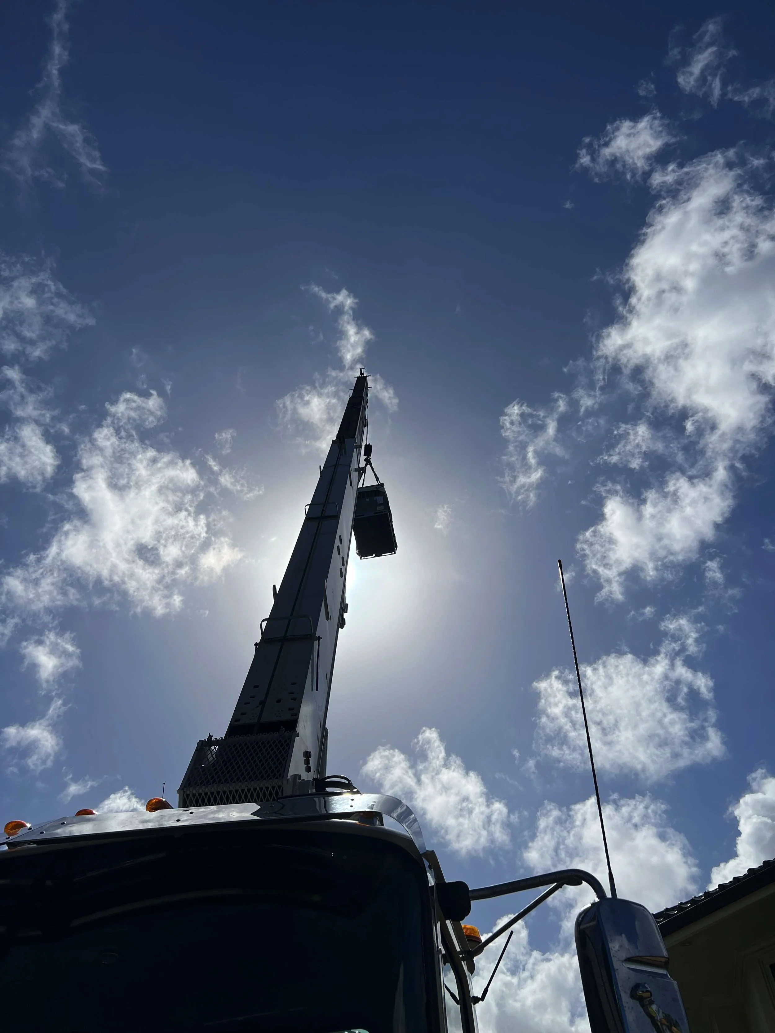 New AC unit being raised by a crane above a truck