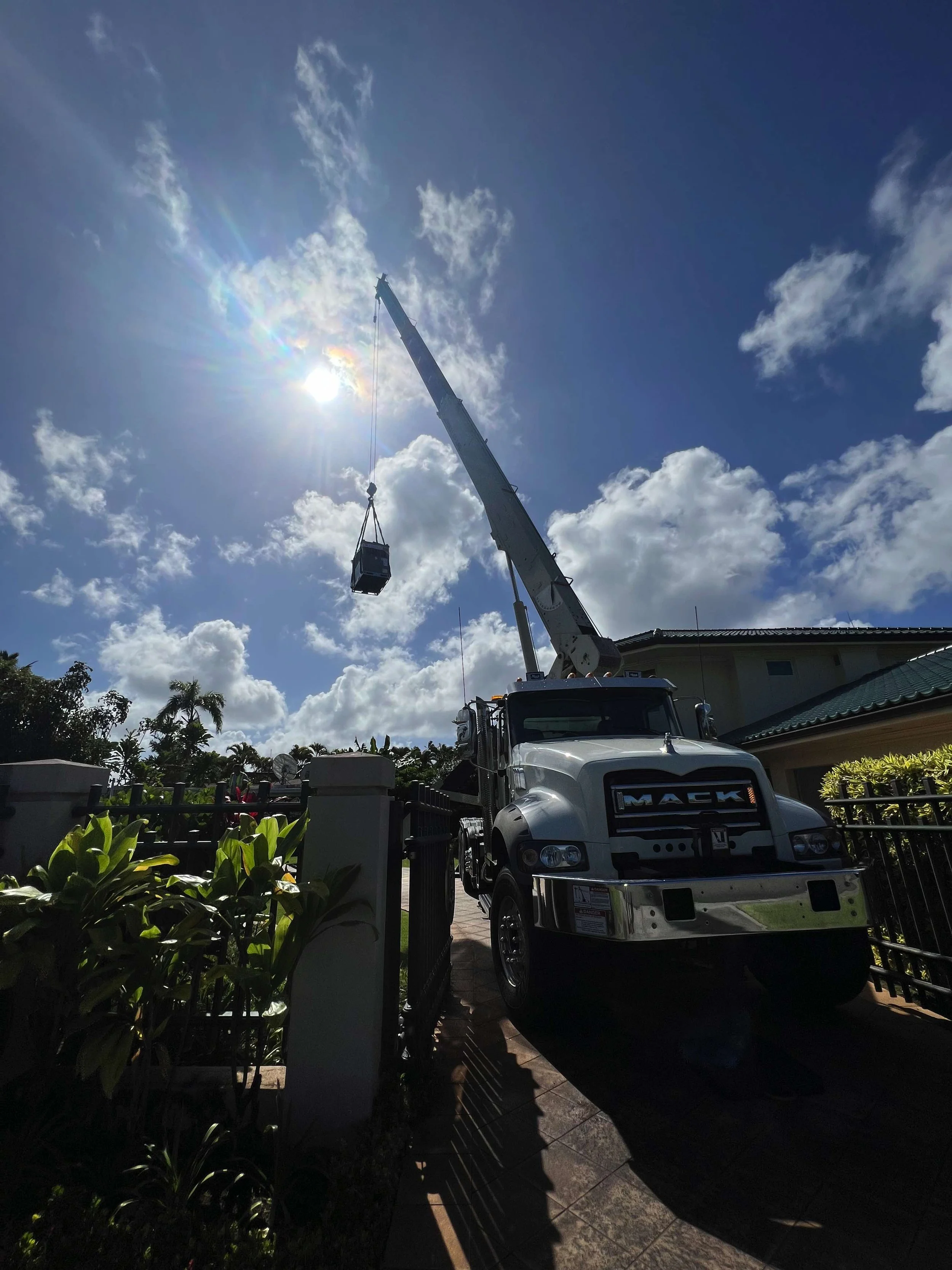 Crane hoisting a new AC system onto a rooftop.