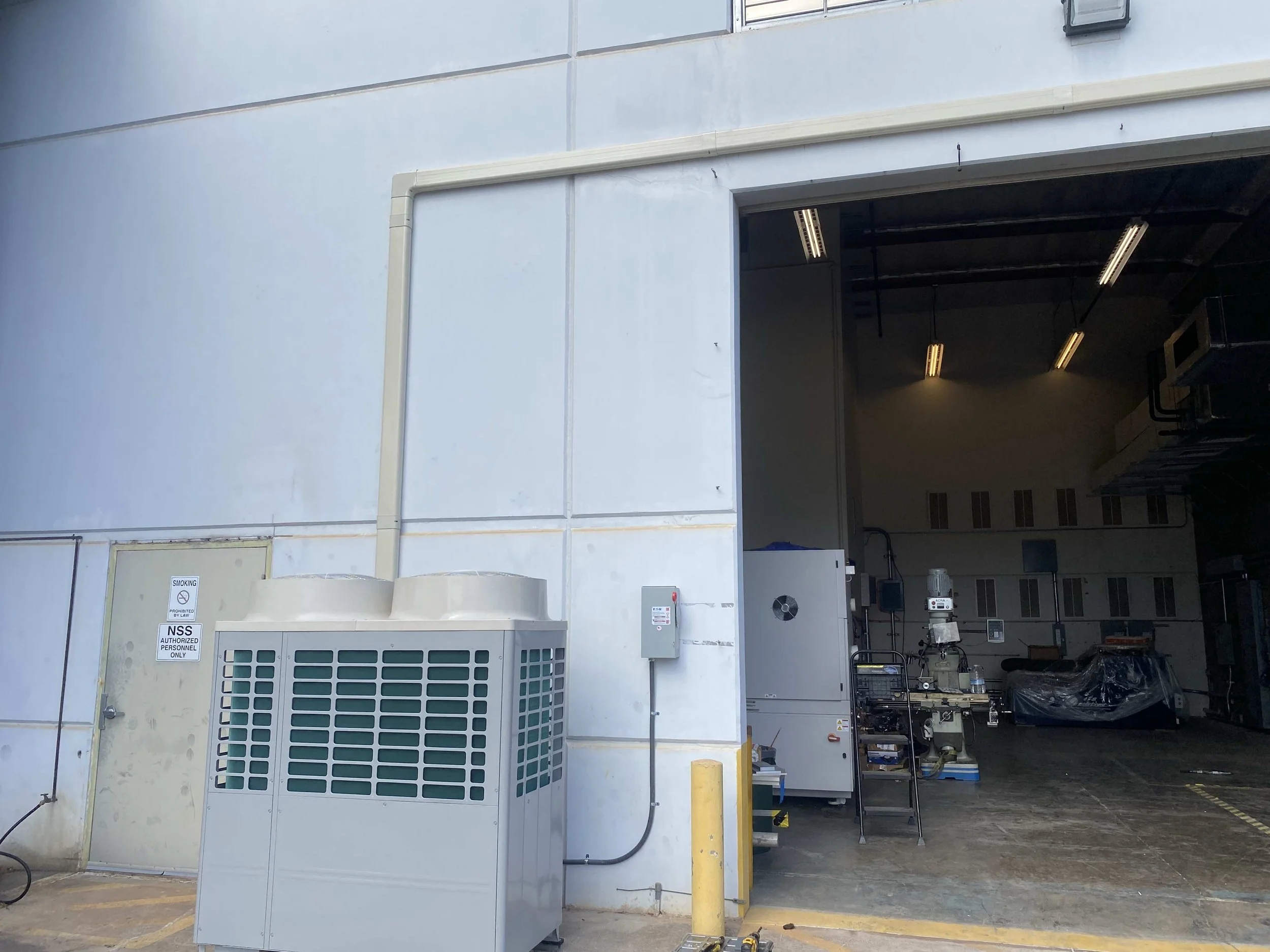 Newly installed outdoor commercial AC unit, connected to interior piping