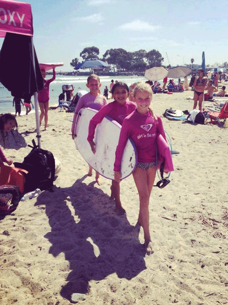 Girls holding the board at surf camp
