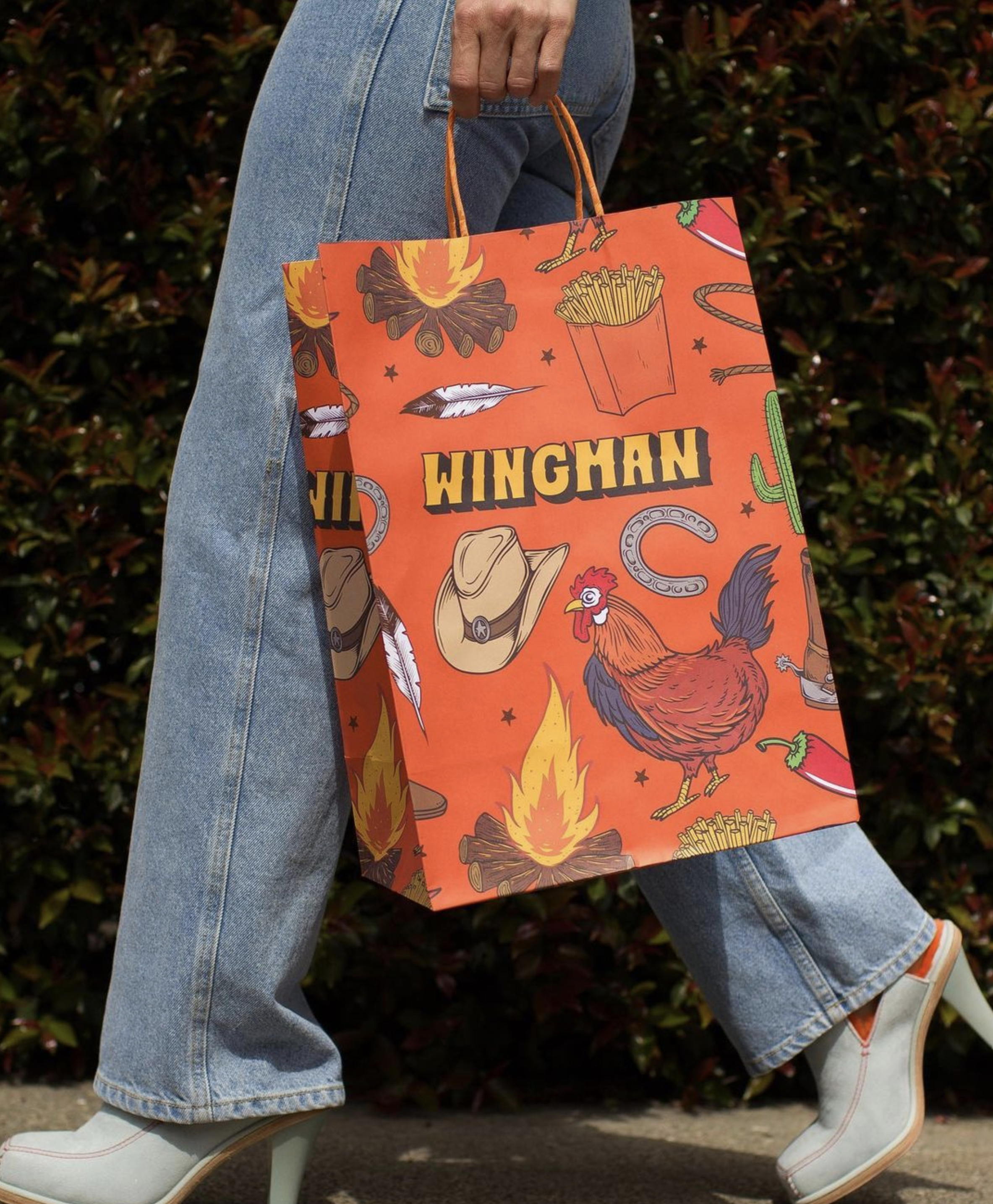 Wingman Rodeo fast food bag design. The illustrated vector pattern pictures a cowboy's hat, a chicken, some french fries, a bonfire, some red pepper and a cactus. 