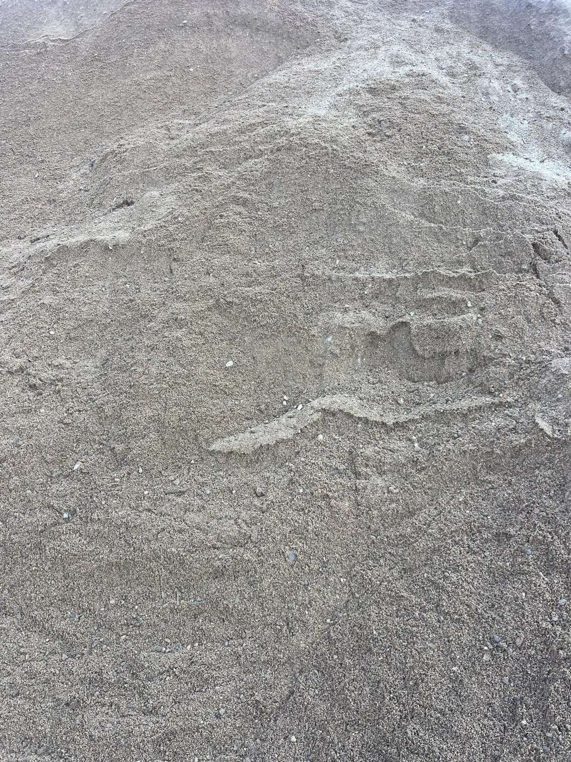 Close-up of a stockpile of manufactured sand (M Sand), a finely crushed granite sand used for pavers, leveling, pipe bedding, and construction projects.