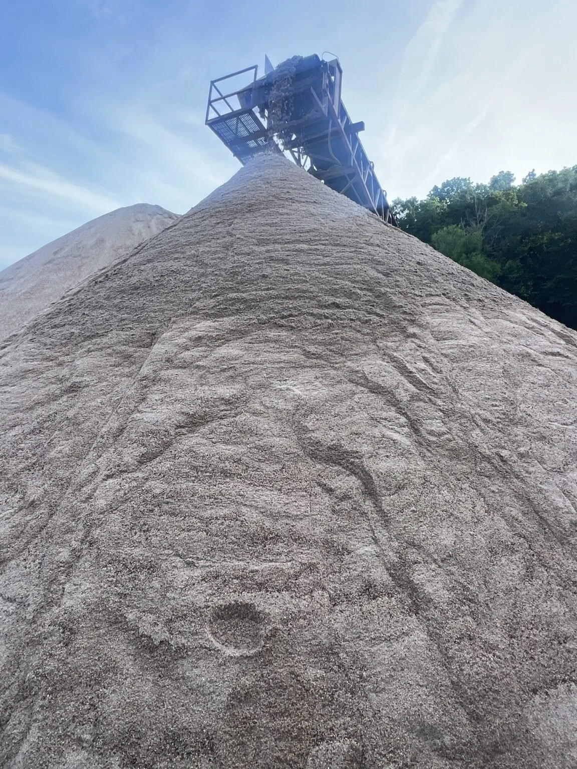 River sand being discharged from a conveyor belt into a stockpile at an aggregate yard.