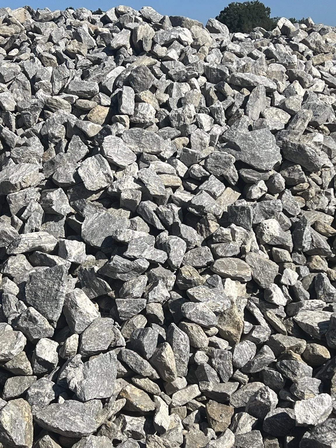 Pile of Class A rip rap granite stone showing large angular rock pieces used for erosion control, drainage, and slope stabilization.