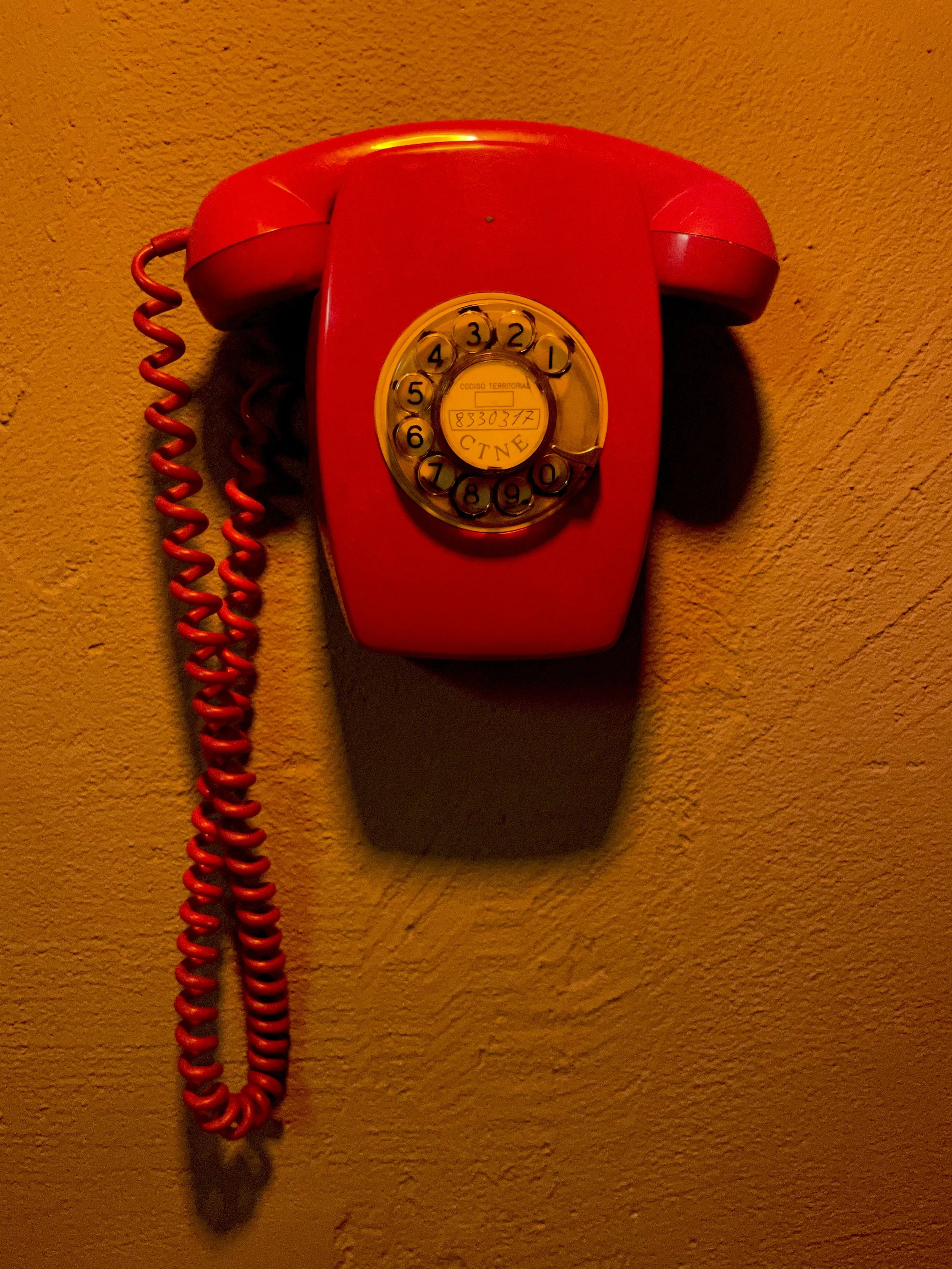 Red telephone on an orange wall