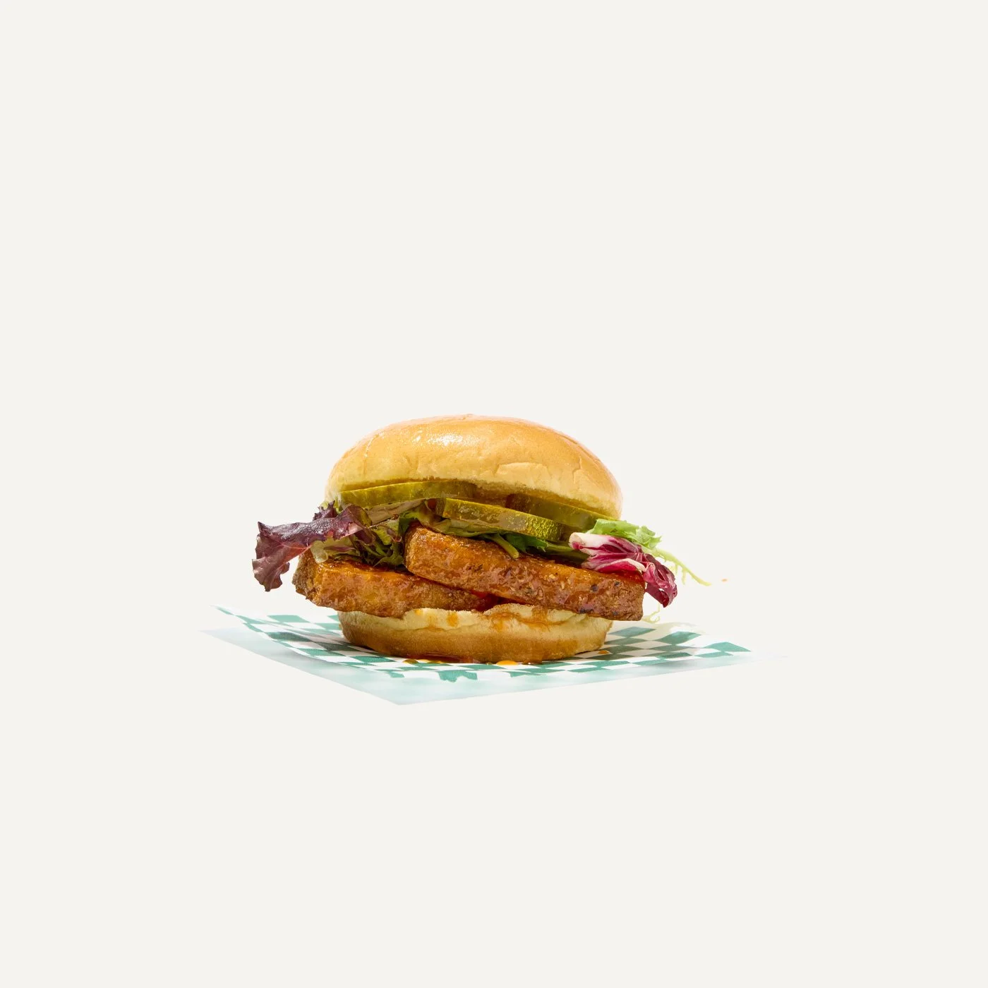 A hot honey crispy tofu sandwich with pickles, lettuce, and a soft bun.