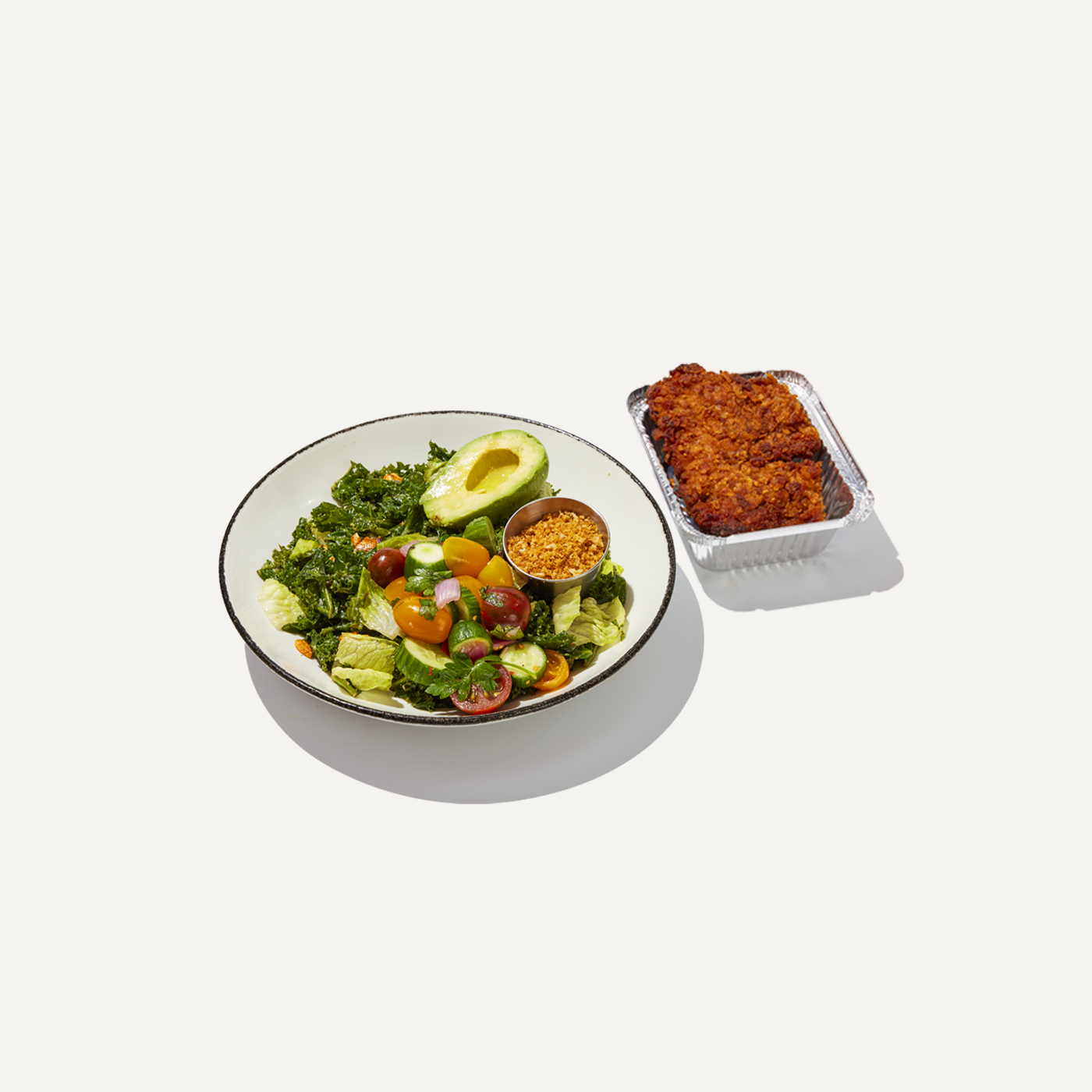 DIG Kale Caesar Salad with avocado, tomatoes, cucumbers, crunchy topping, and crispy chicken.