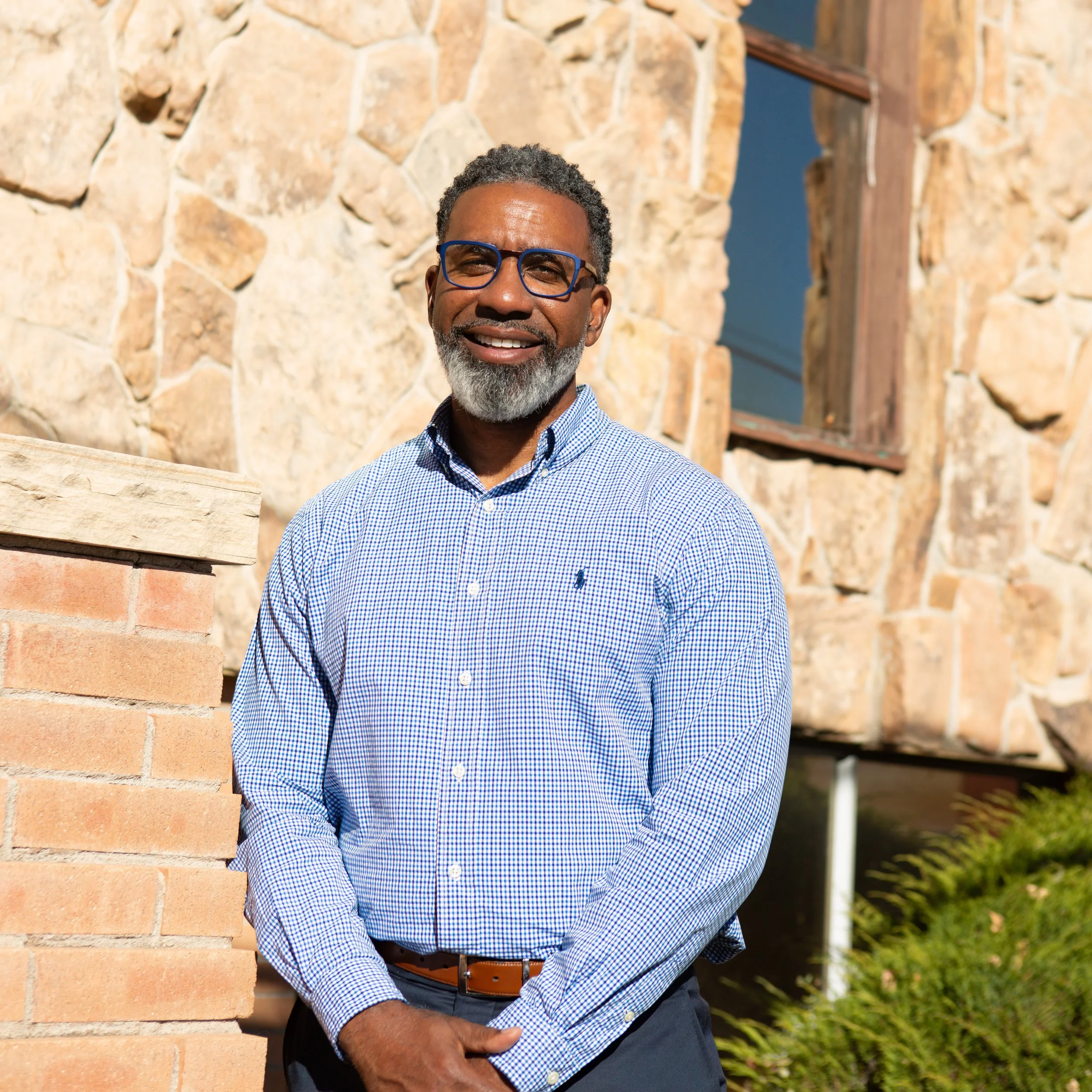 Pastor Derrick Kelsey standing outside the cobblestone building smiling