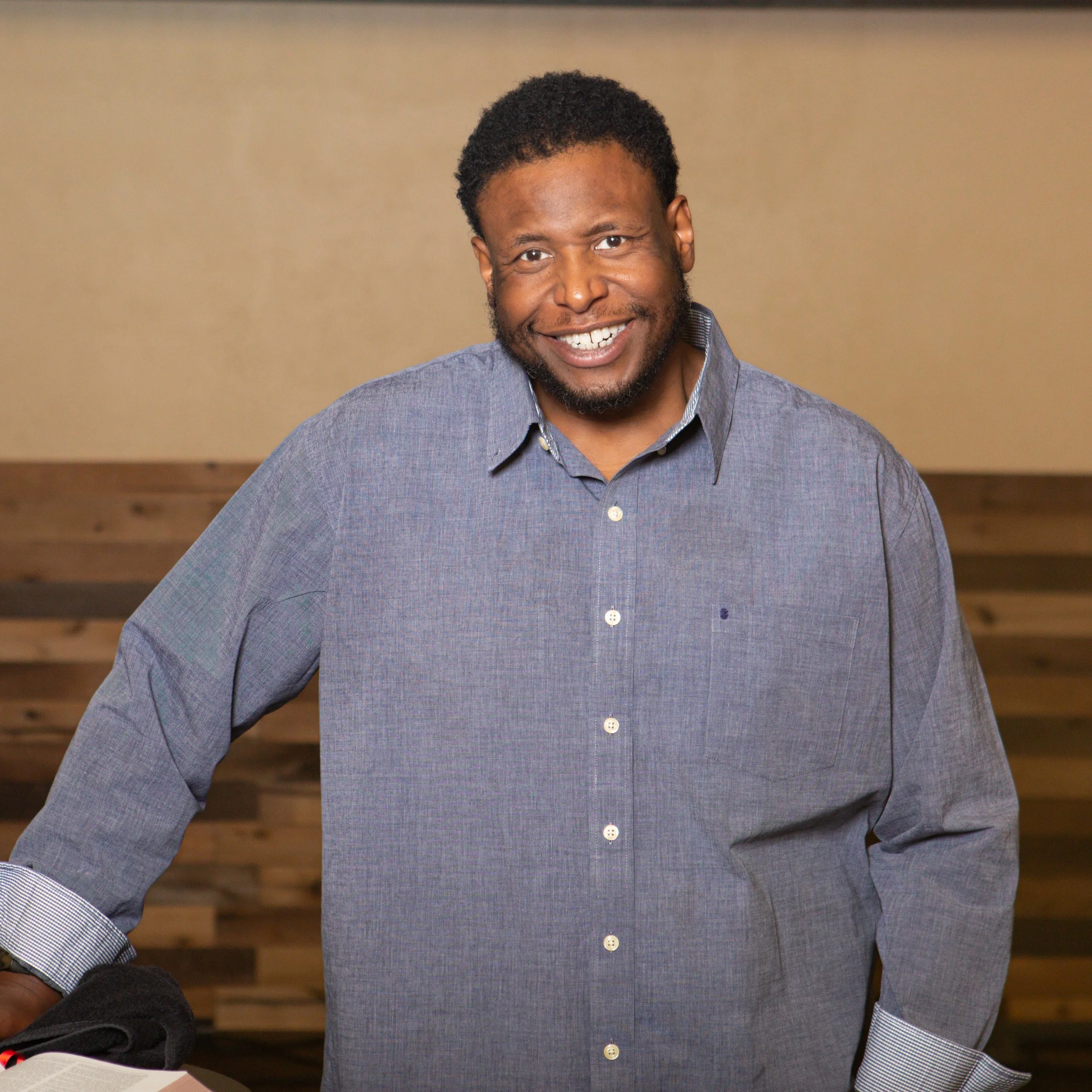 Pastor Brandon Washington standing next to the podium on stage smiling leaning against the podium
