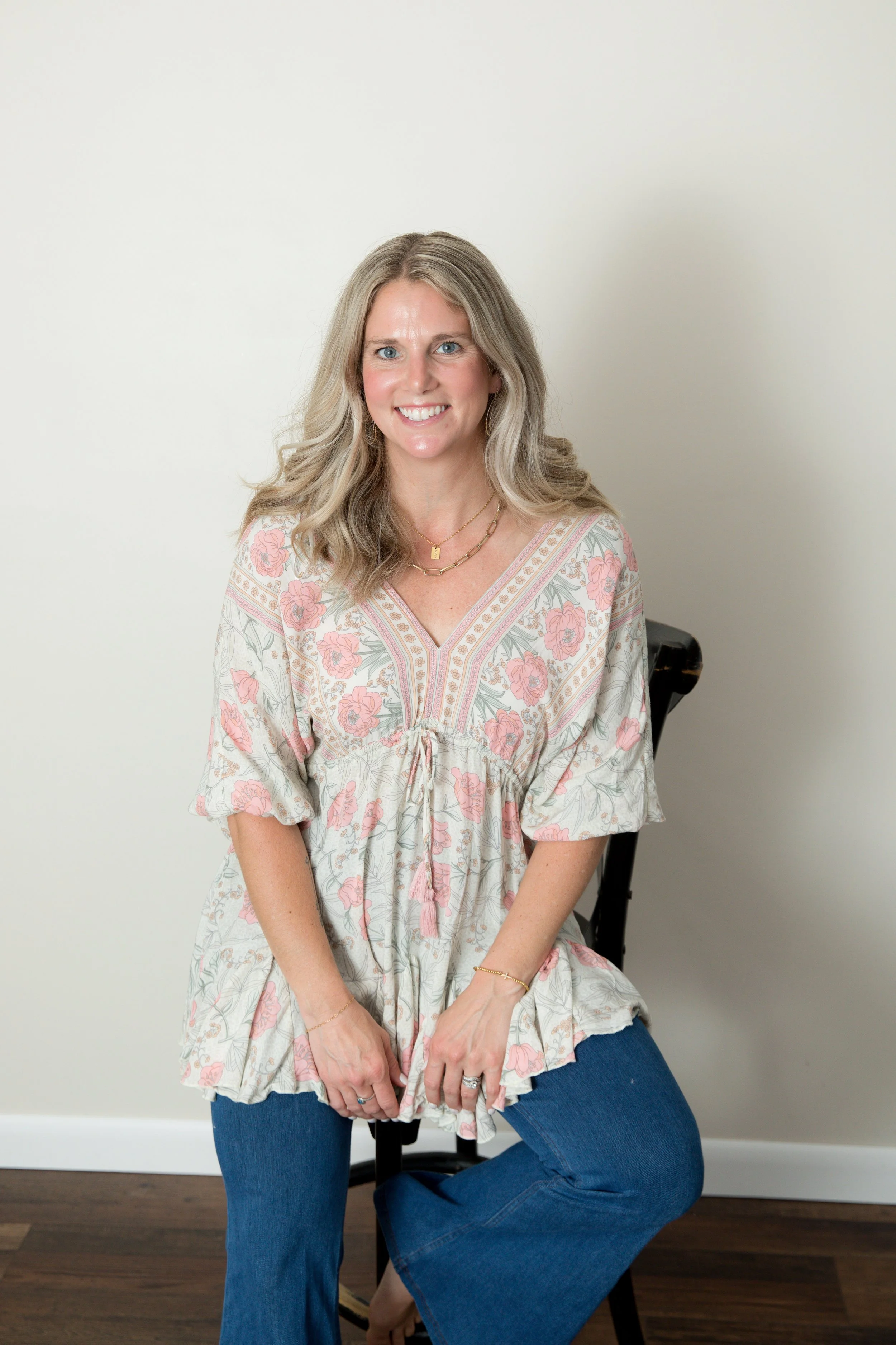 A woman with long blonde hair smiling against a plain white background.