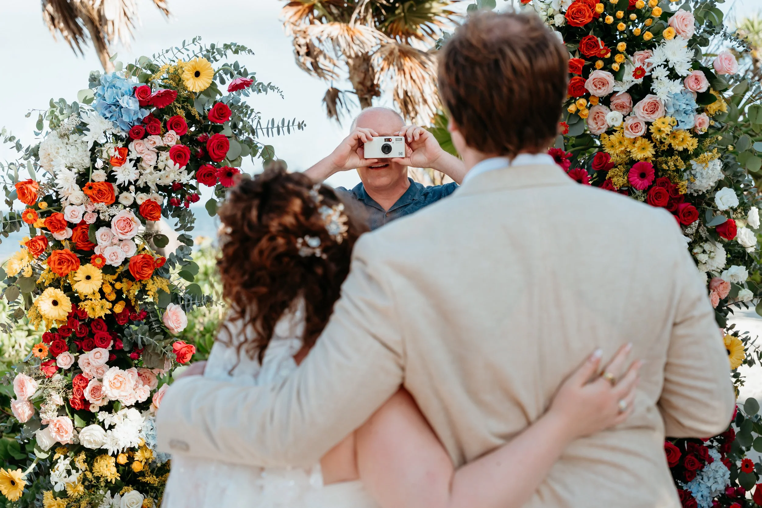 Destination wedding couple, wedding ceremony, vintage camera, vintage photos, floral arch, Valentin Imperial Riviera Maya, Mexico