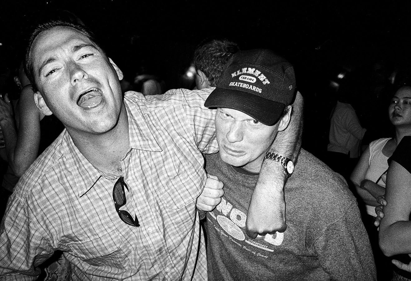 Mike Sinclair in a headlock, laughing with a friend at a social gathering