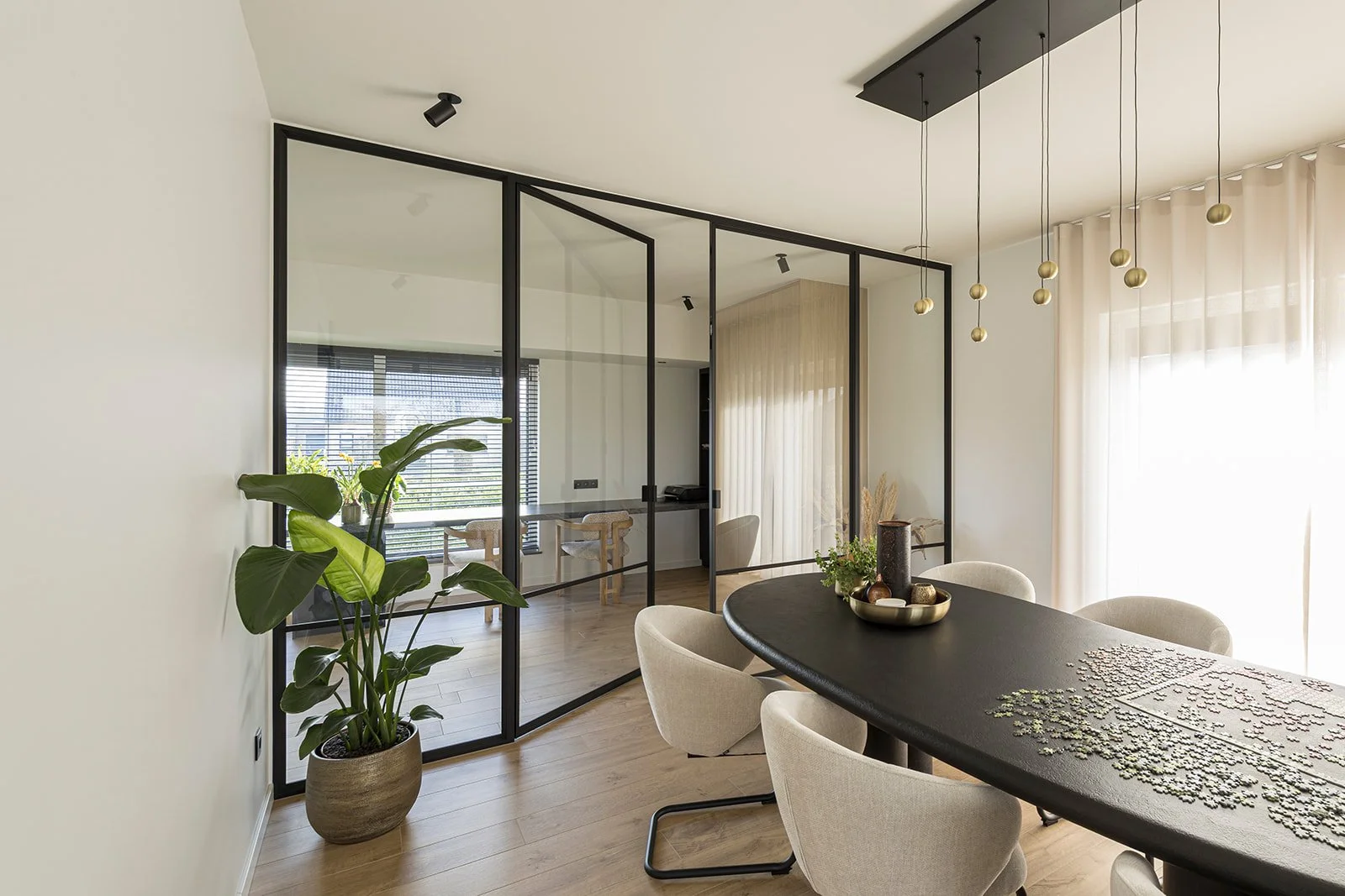 Een stalen scheidingswand met een dubbele stalen scharnierdeur met helder glas in een moderne gerenoveerde woning in de gemeente Dessel